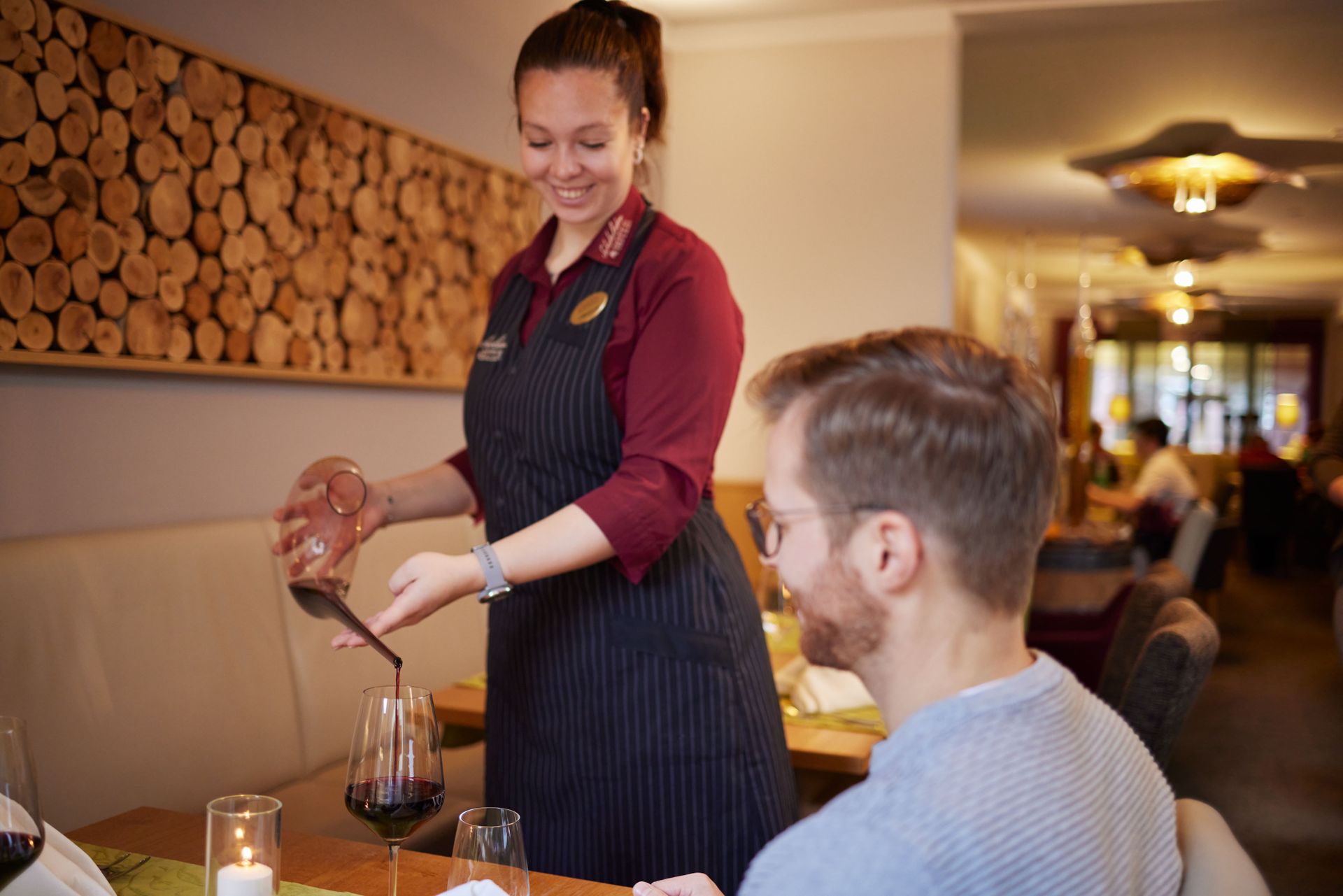 In einem Restaurant schenkt eine Frau einem Mann Wein in ein Glas ein.