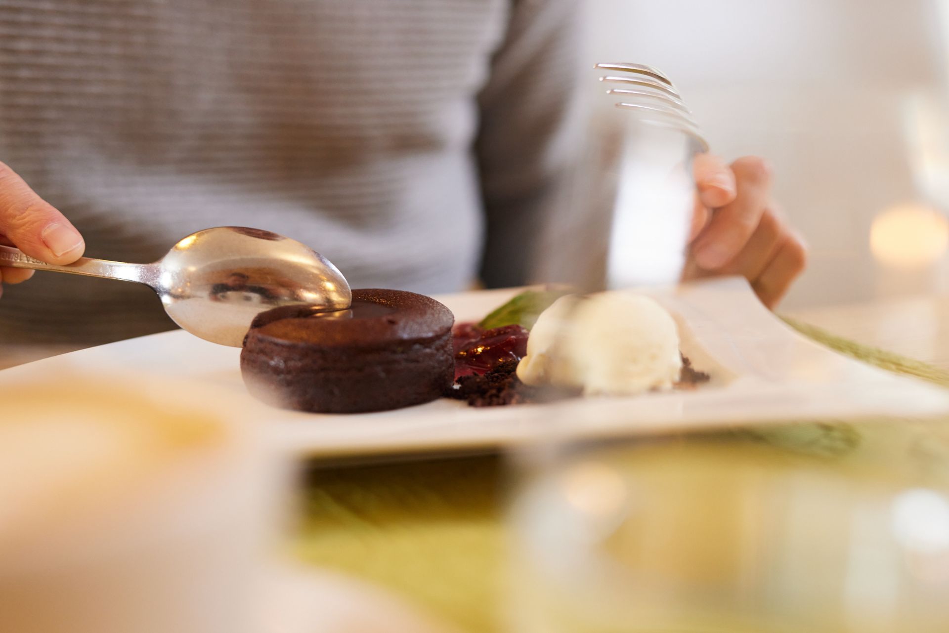 Eine Person isst ein Dessert mit Löffel und Gabel