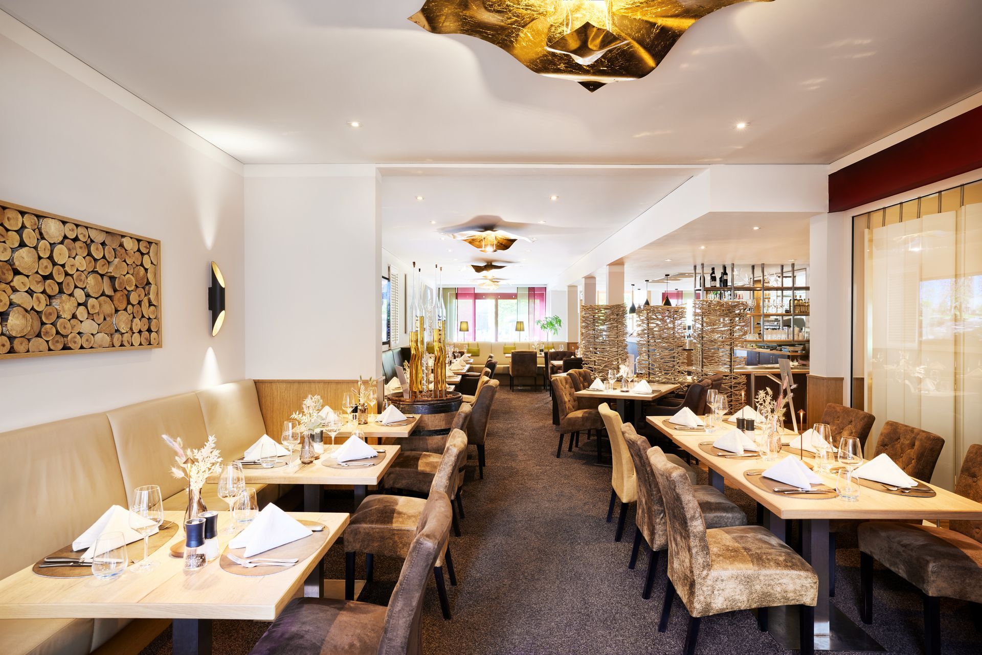 Restaurantinterieur mit gedeckten Tischen, neutralen Farbtönen und dekorativer Beleuchtung.