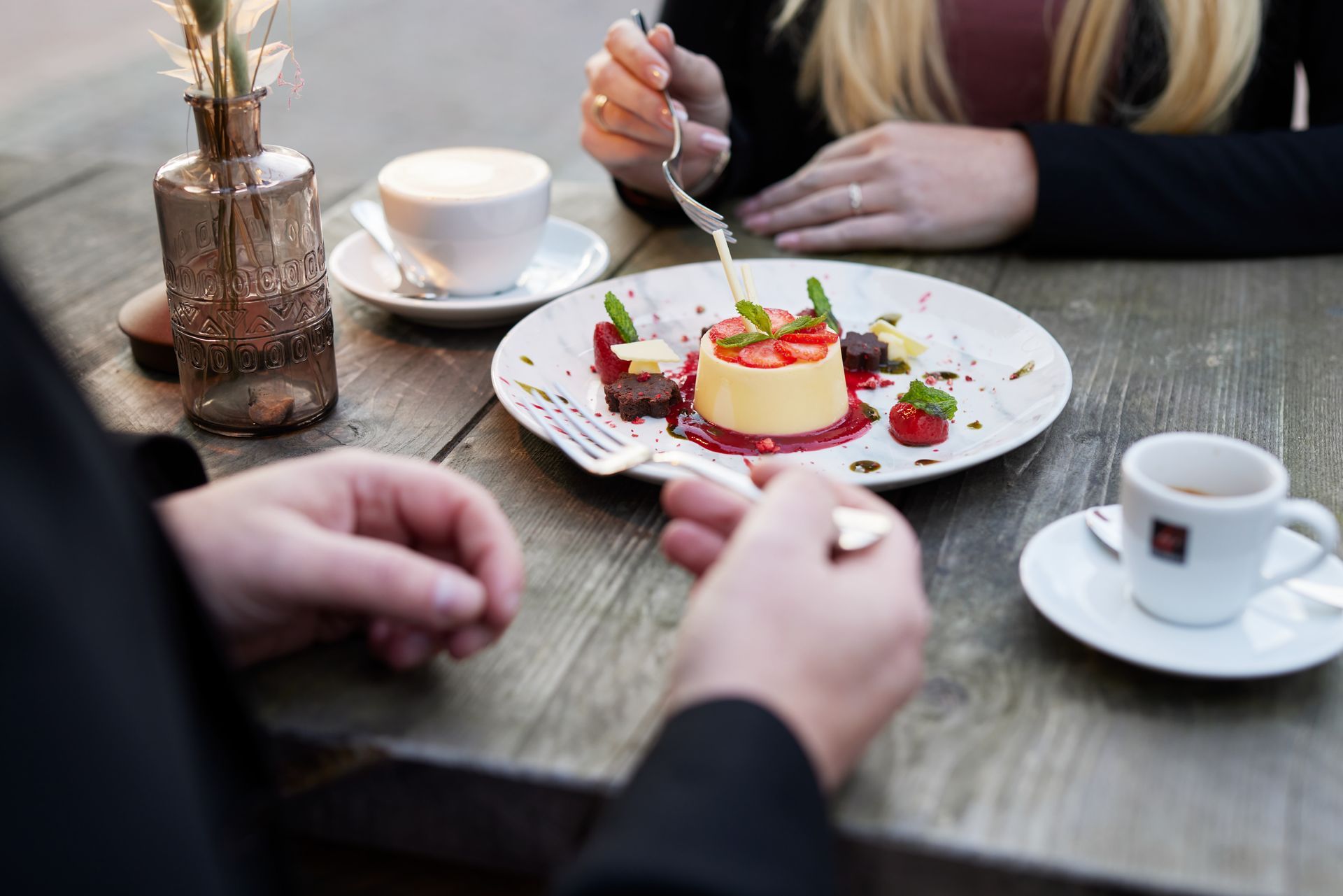 Ein Mann und eine Frau sitzen an einem Tisch und essen Nachtisch.