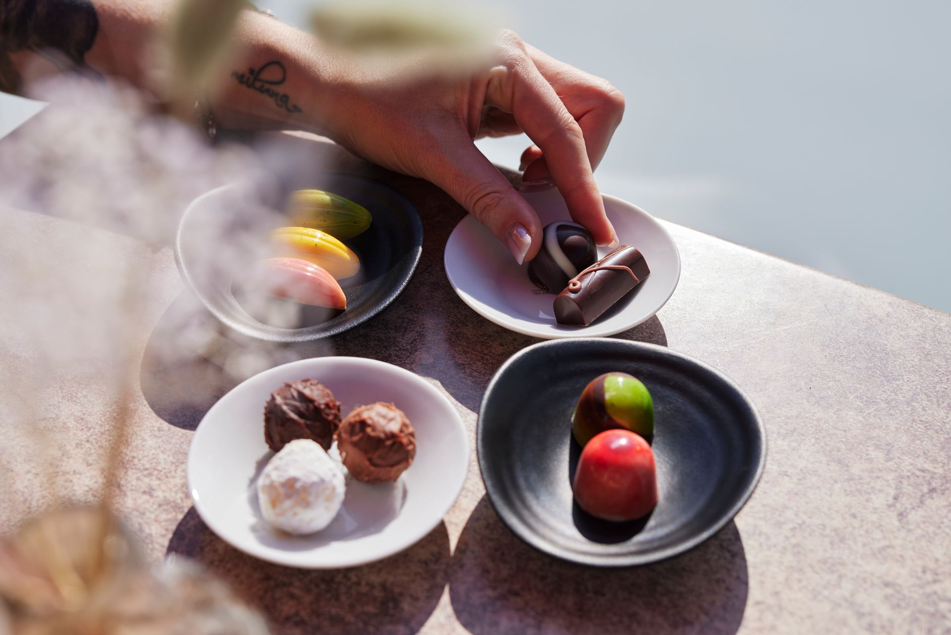 Close-up of colorful, homemade chocolates and a hand reaching for them