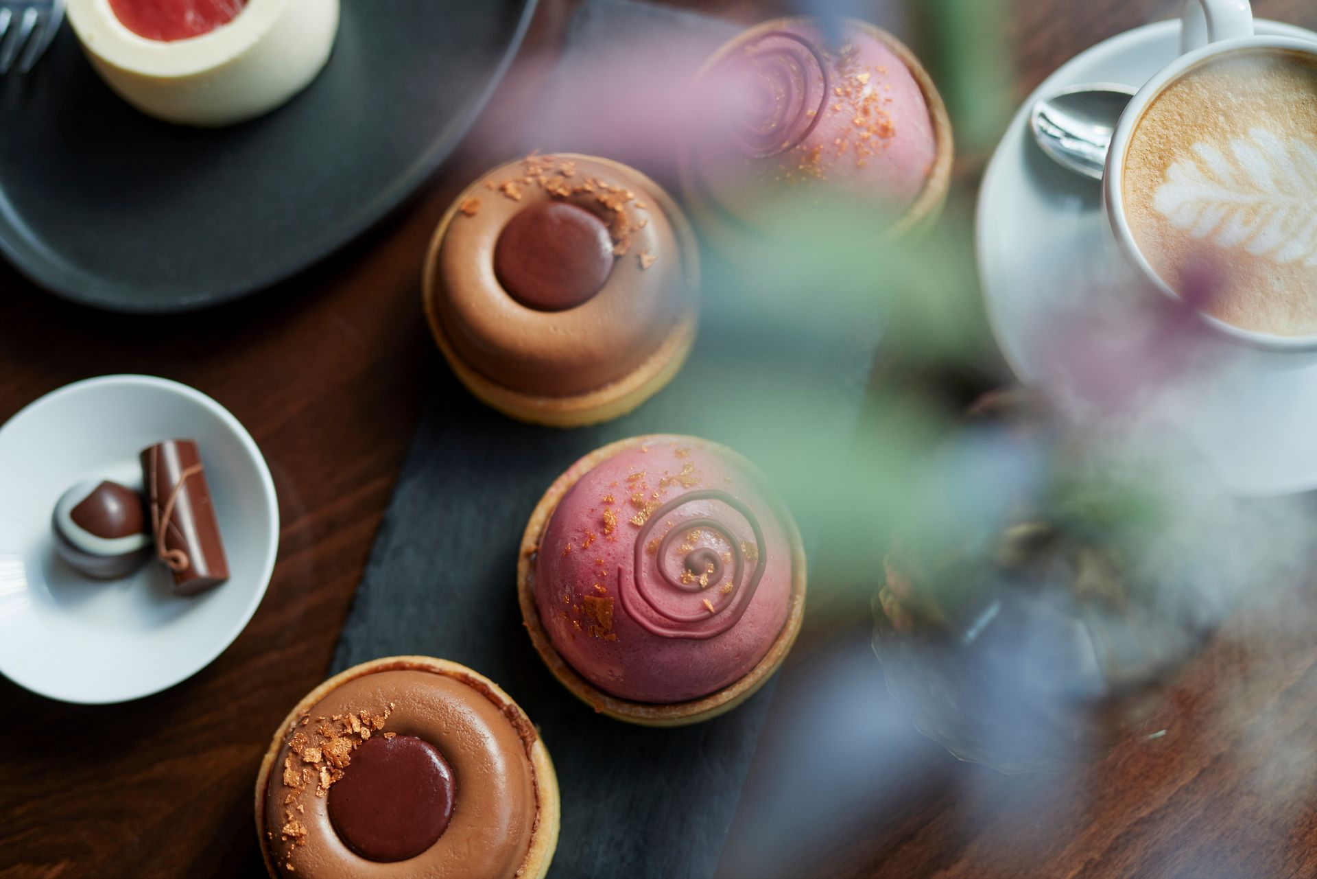 Ein Tisch mit einer Auswahl an Desserts und einer Tasse Kaffee.