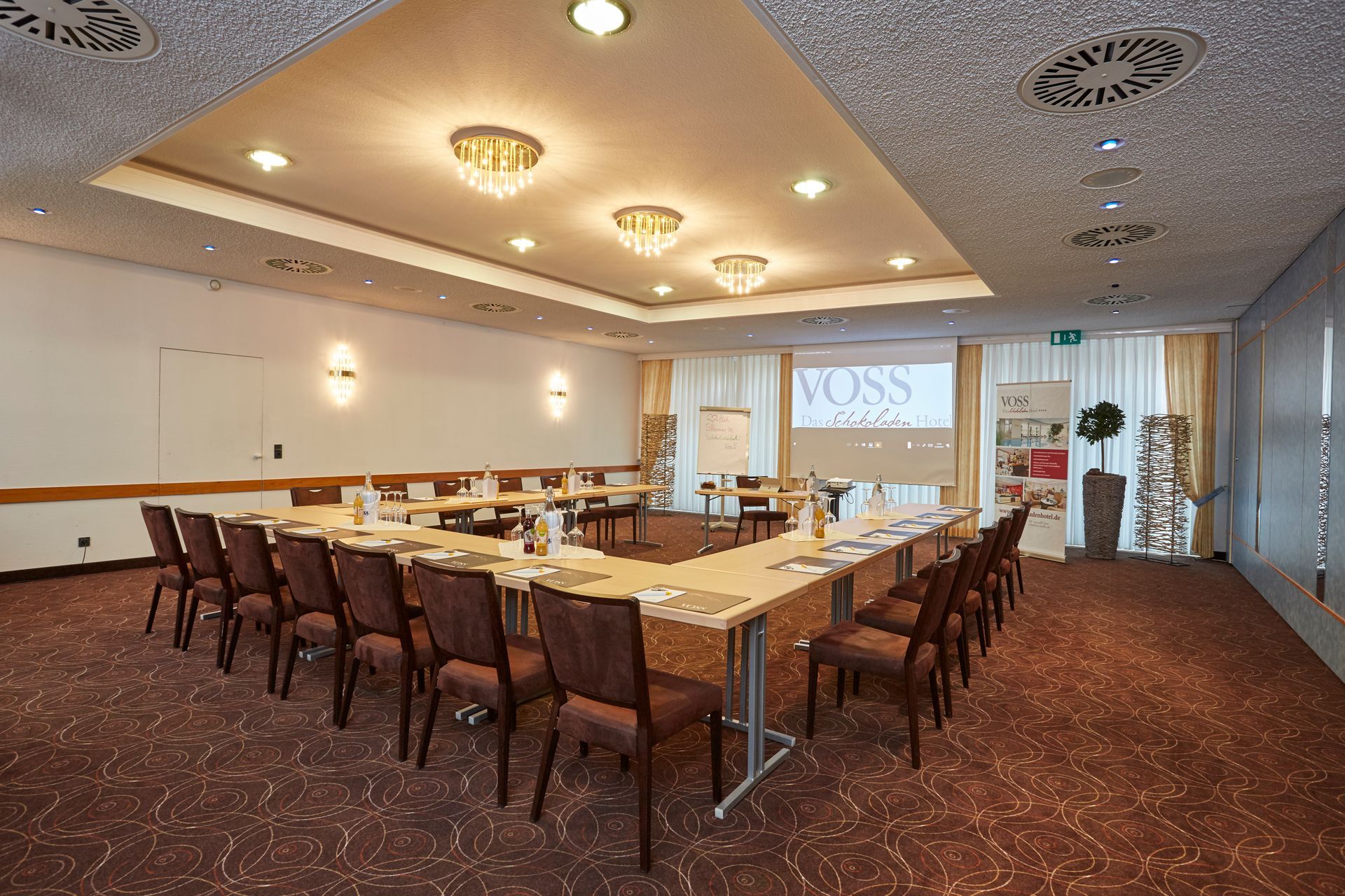 Ein großer Konferenzraum mit Tischen und Stühlen sowie einer Projektionsleinwand.