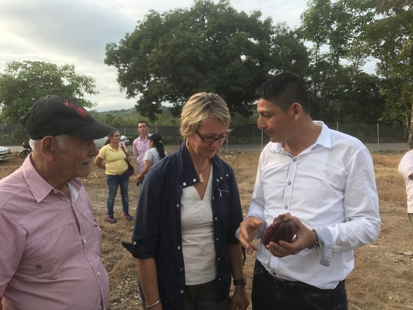 Eine Gruppe von Leuten steht auf einem Feld und unterhält sich über Kakaobohnen