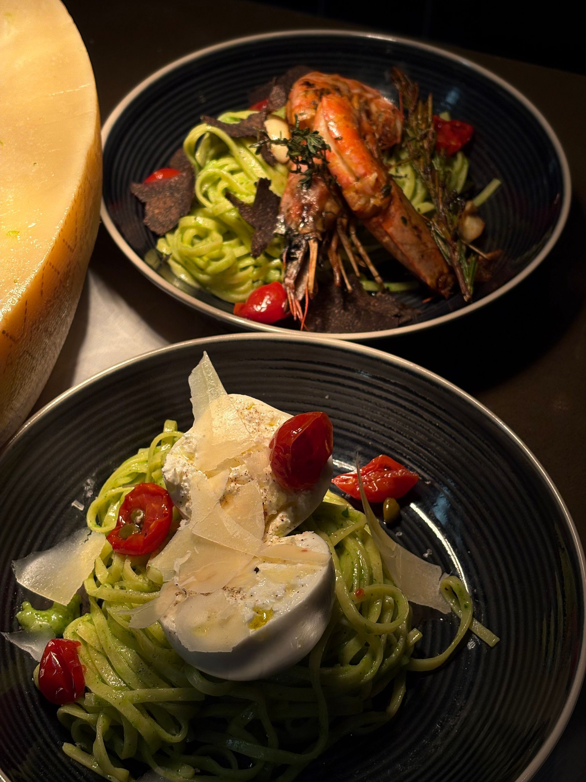 Zwei Schüsseln Pasta mit Garnelen, Kräutern und roten Chilischoten auf einem Tisch.