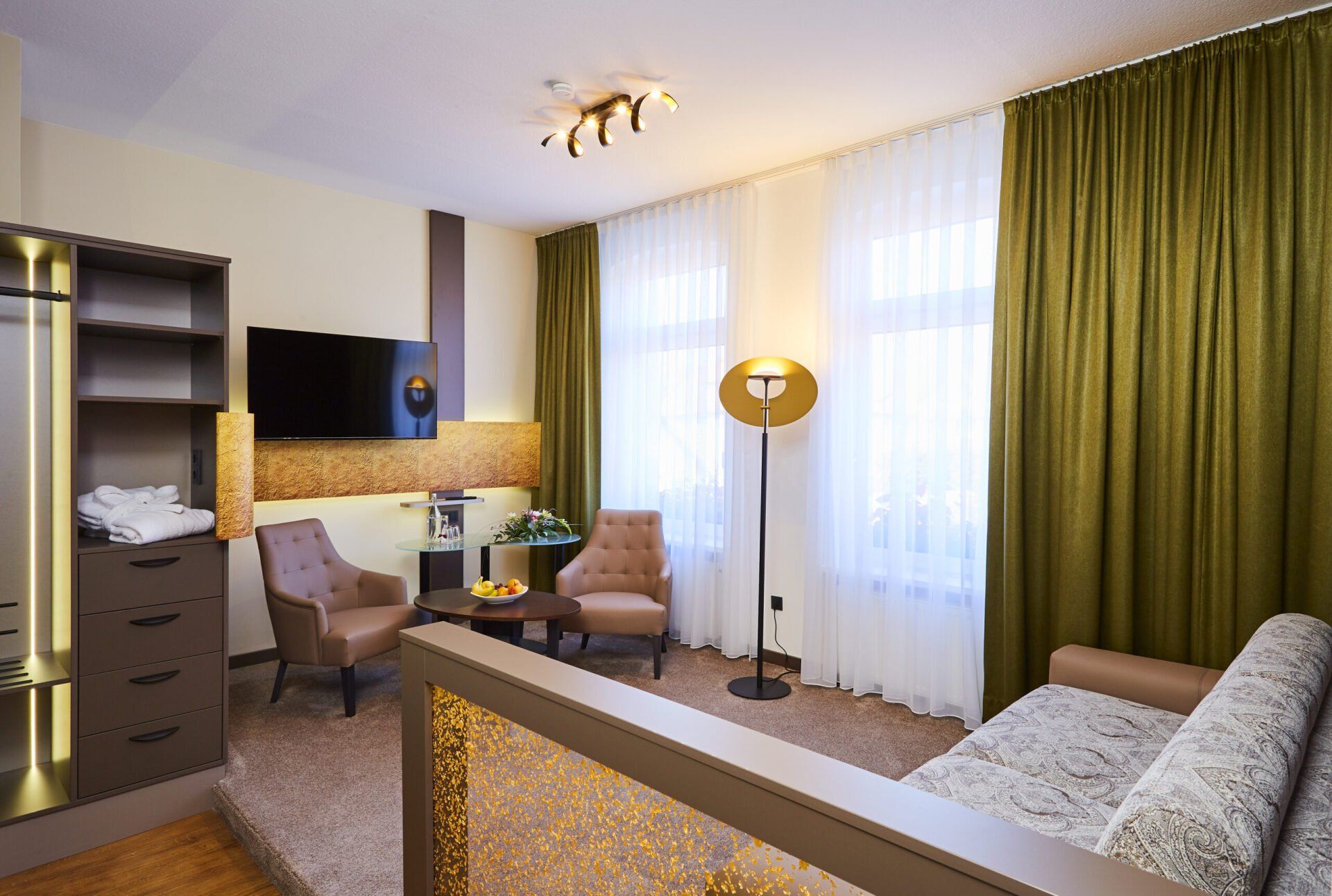 Ein Wohnzimmer mit Couch, Sesseln und Fernseher.