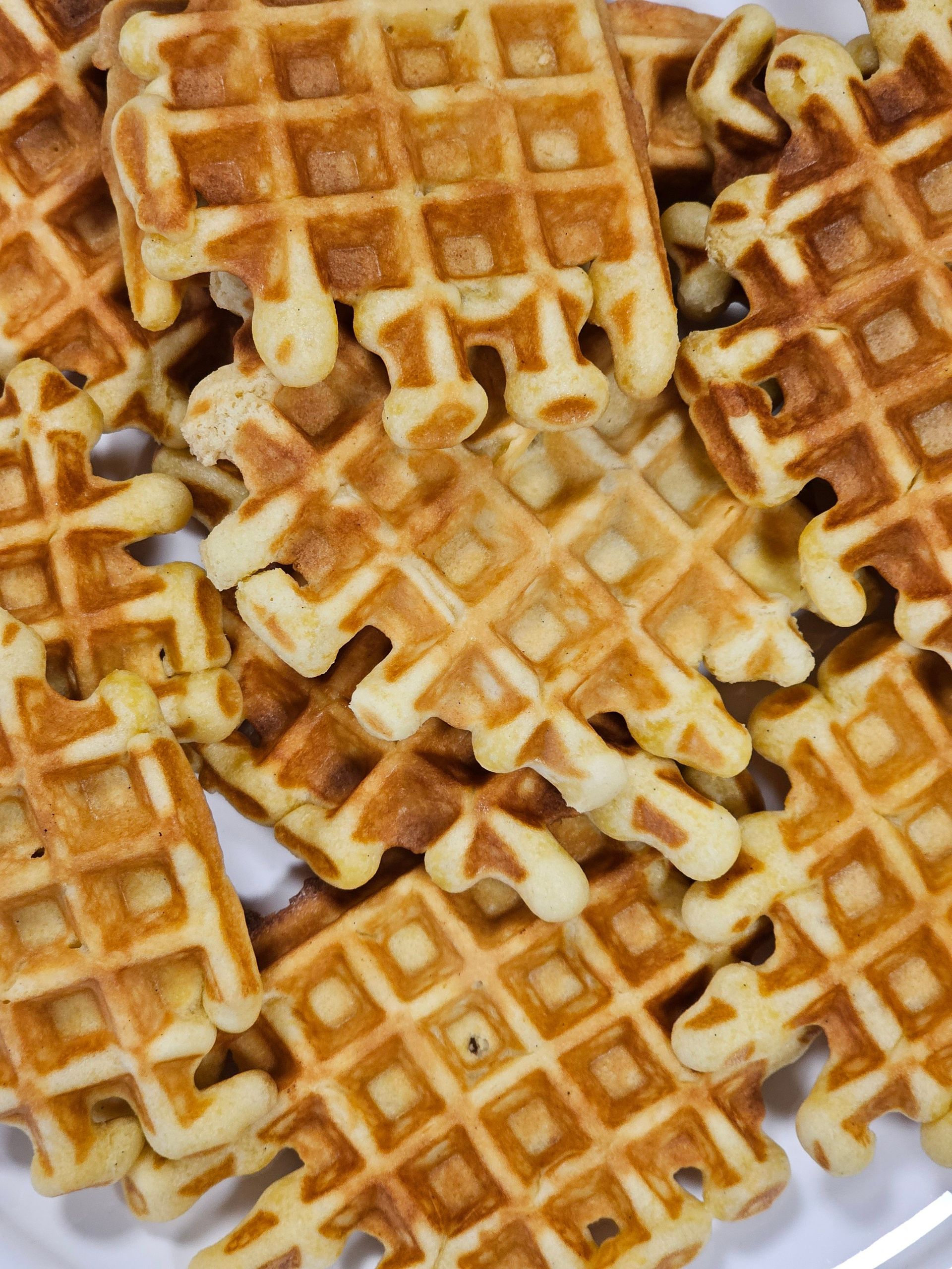Ein Stapel goldbrauner Waffeln, mit Puderzucker bestäubt, auf einem weißen Teller im Schokoladenhotel.