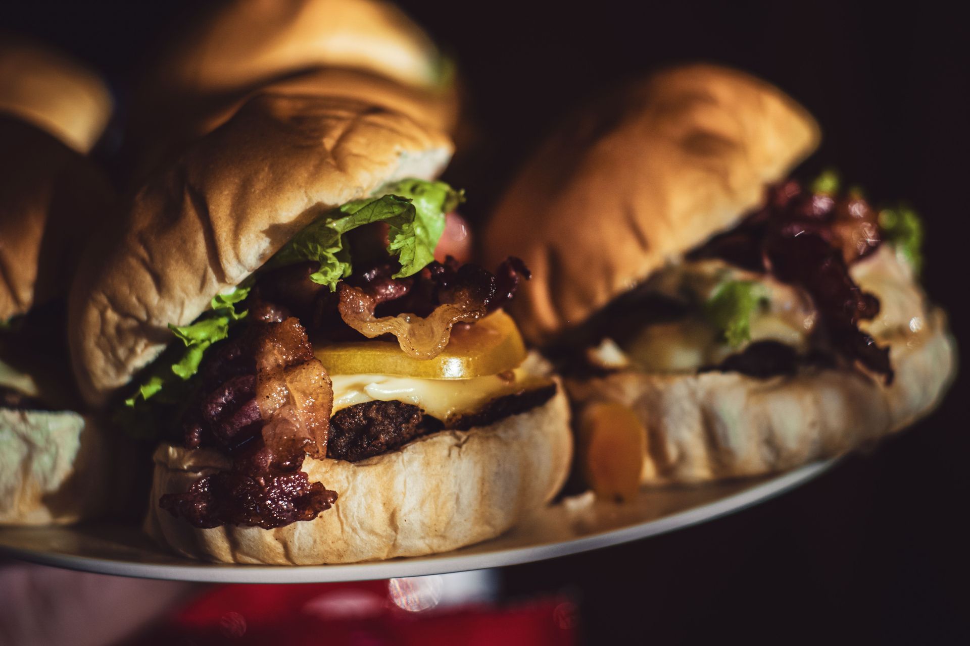 Gourmet-Slider mit Salat, Käse und Speck auf einem Teller in warmem Licht