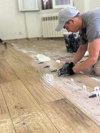 Un cubo de pintura está sobre un suelo de baldosas, al lado de una barandilla.