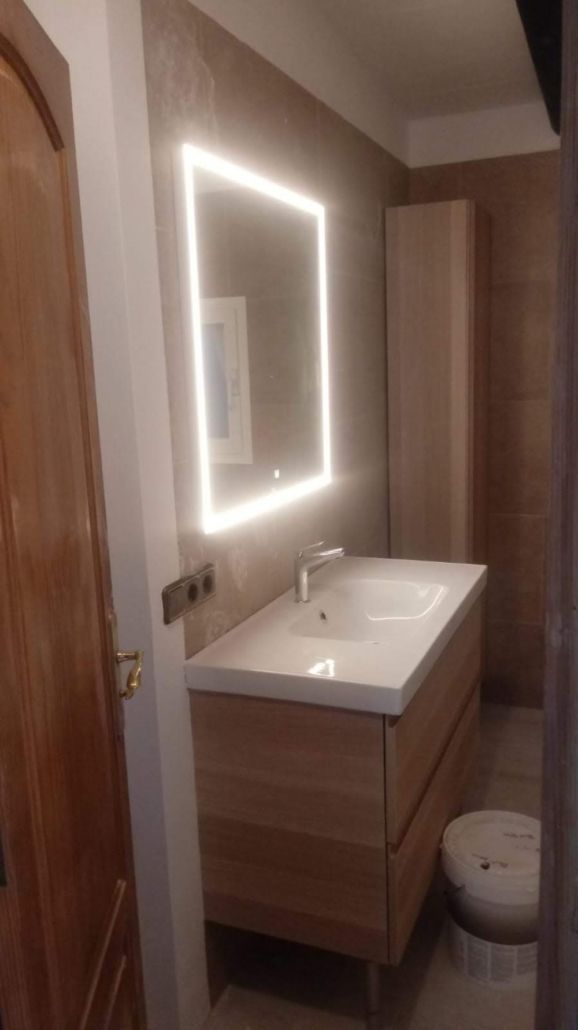 Un baño con lavabo, espejo e inodoro.