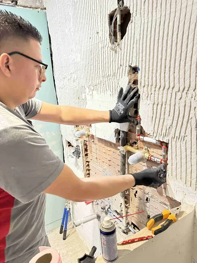 Un hombre está trabajando en una tubería en un baño.