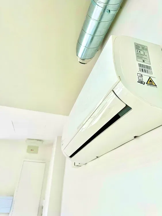 Un acondicionador de aire blanco cuelga del techo de una habitación.