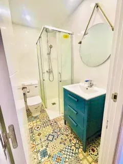 Un baño con lavabo, inodoro, ducha y espejo.