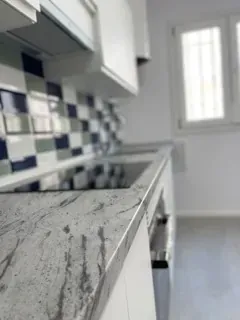 Una cocina con fregadero, estufa, gabinetes y una ventana.