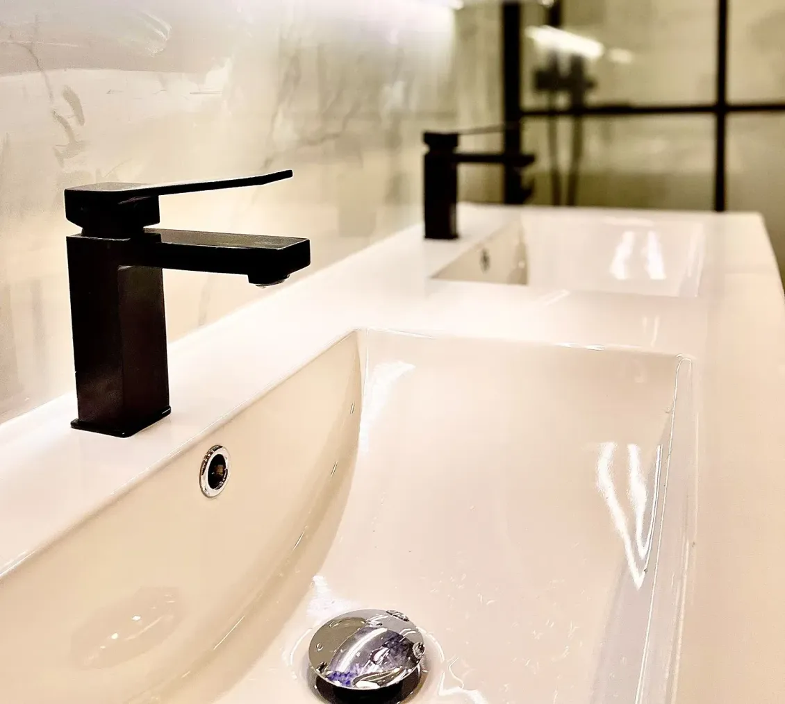 Un baño con dos lavabos y dos grifos negros.