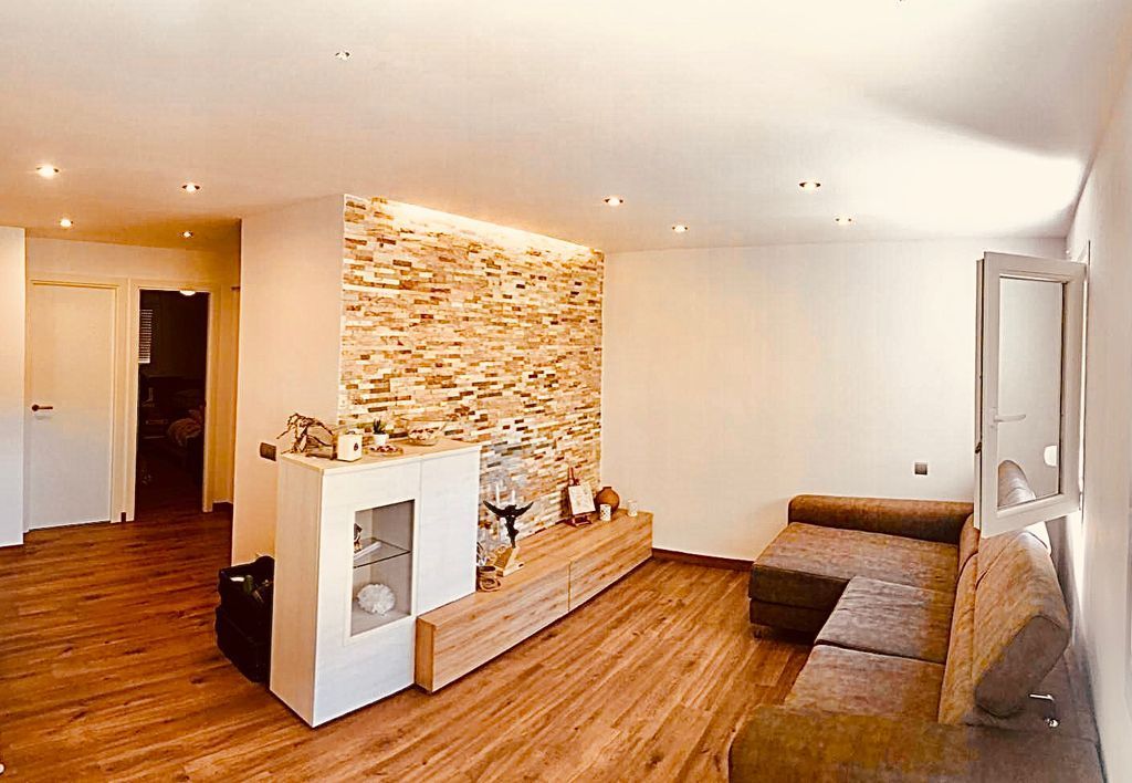 Una sala de estar con sofá, chimenea y una pared de piedra.