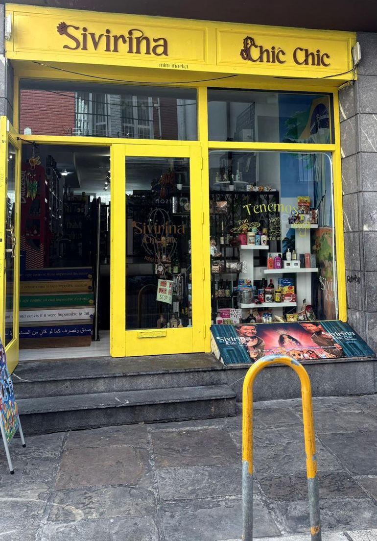 Fachada amarilla de tienda “Sivirina Chic Chic”, con puerta, escaparates y exposición de mercancía.