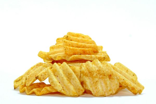 Pila de patatas fritas estriadas, de color marrón dorado con condimentos, sobre un fondo blanco.