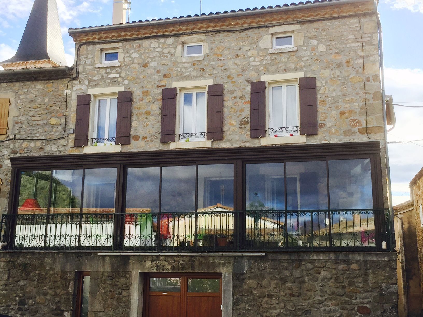 Véranda gris anthracite et vitrée sur balcon et devant maison en pierre