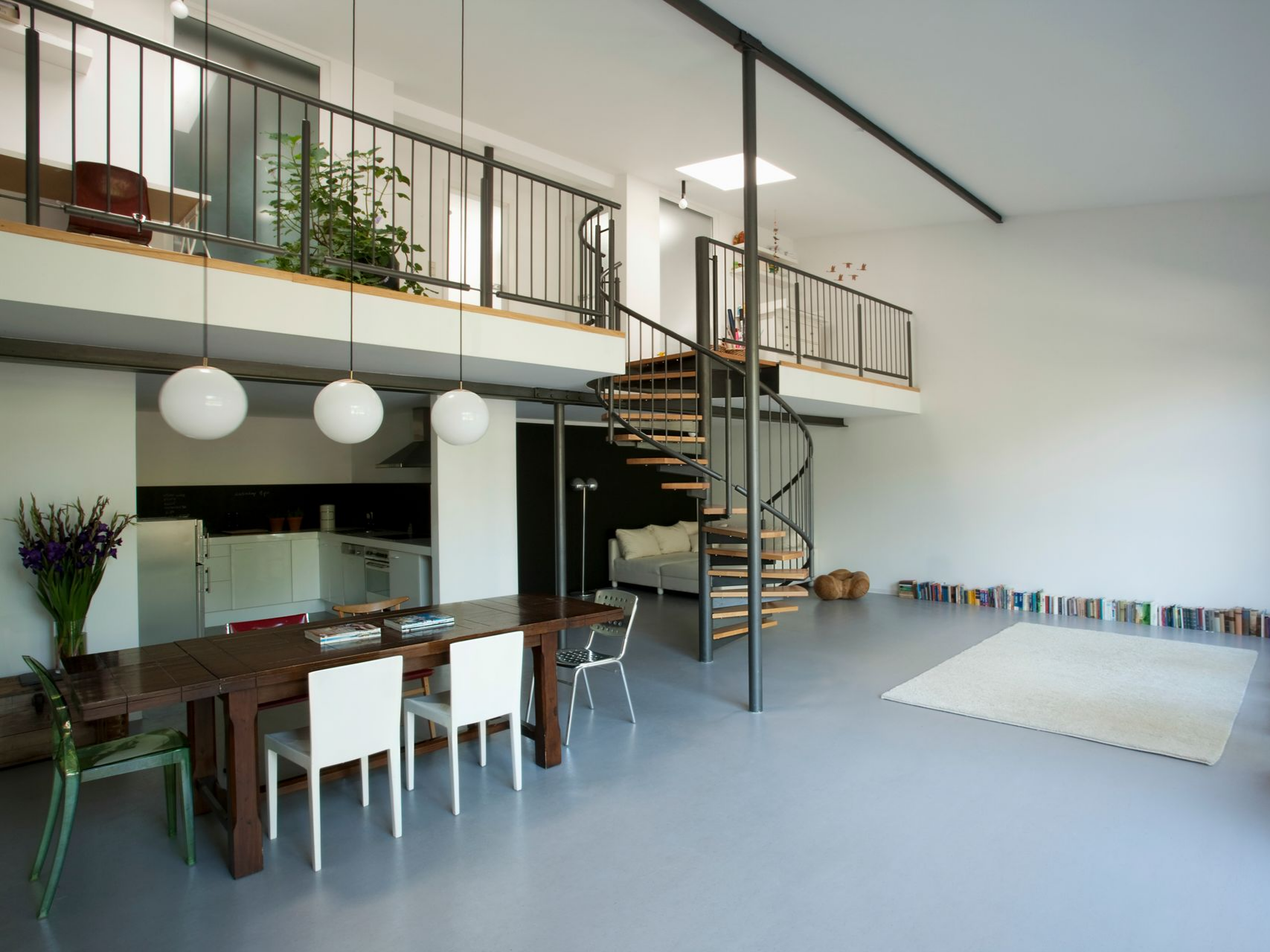 Intérieur de loft moderne avec coin repas, escalier en colimaçon et mezzanine.