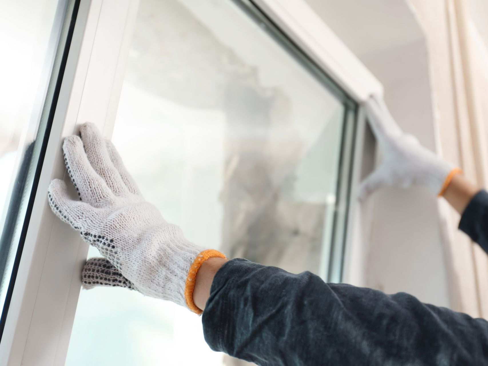Artisan avec des gants en train de remplacer une fenêtre