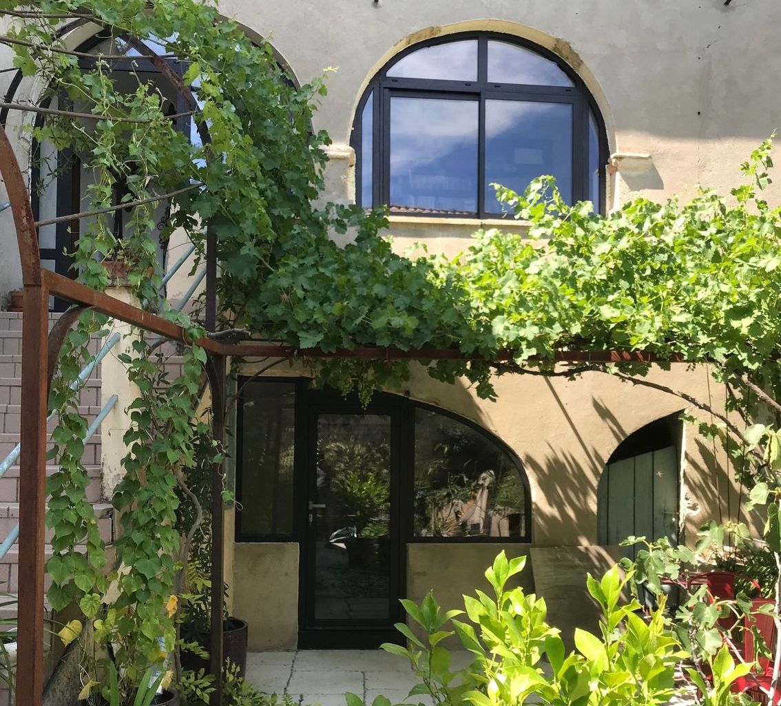 Menuiserie extérieure en PVC noir devant arche de plantes vertes