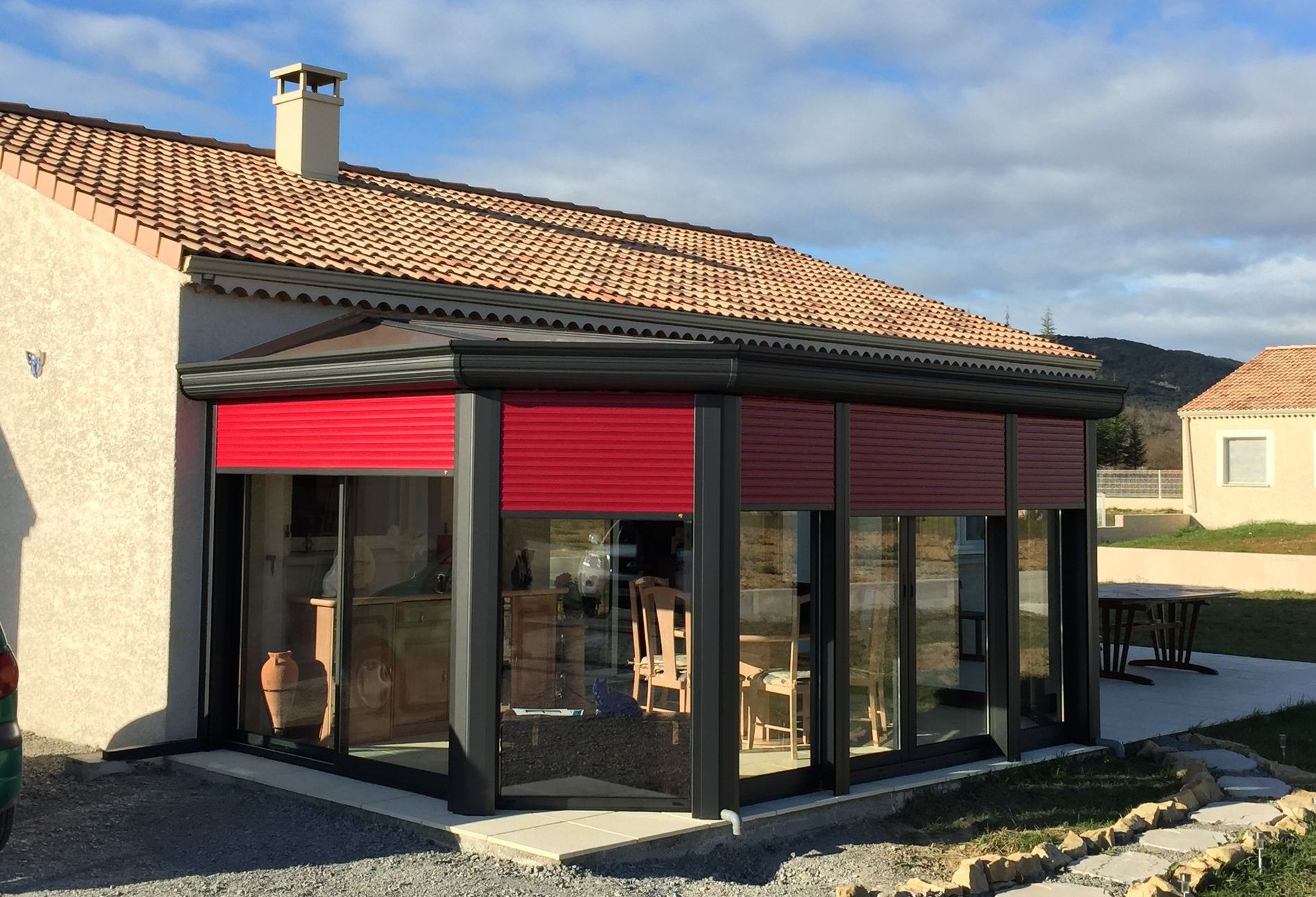 Maison avec véranda noire et store intérieur rouge