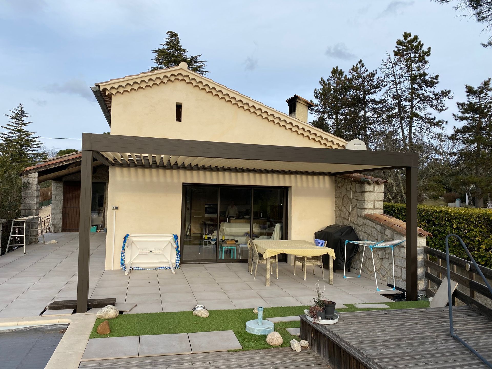 Maison beige avec terrasse en pierre et pergola