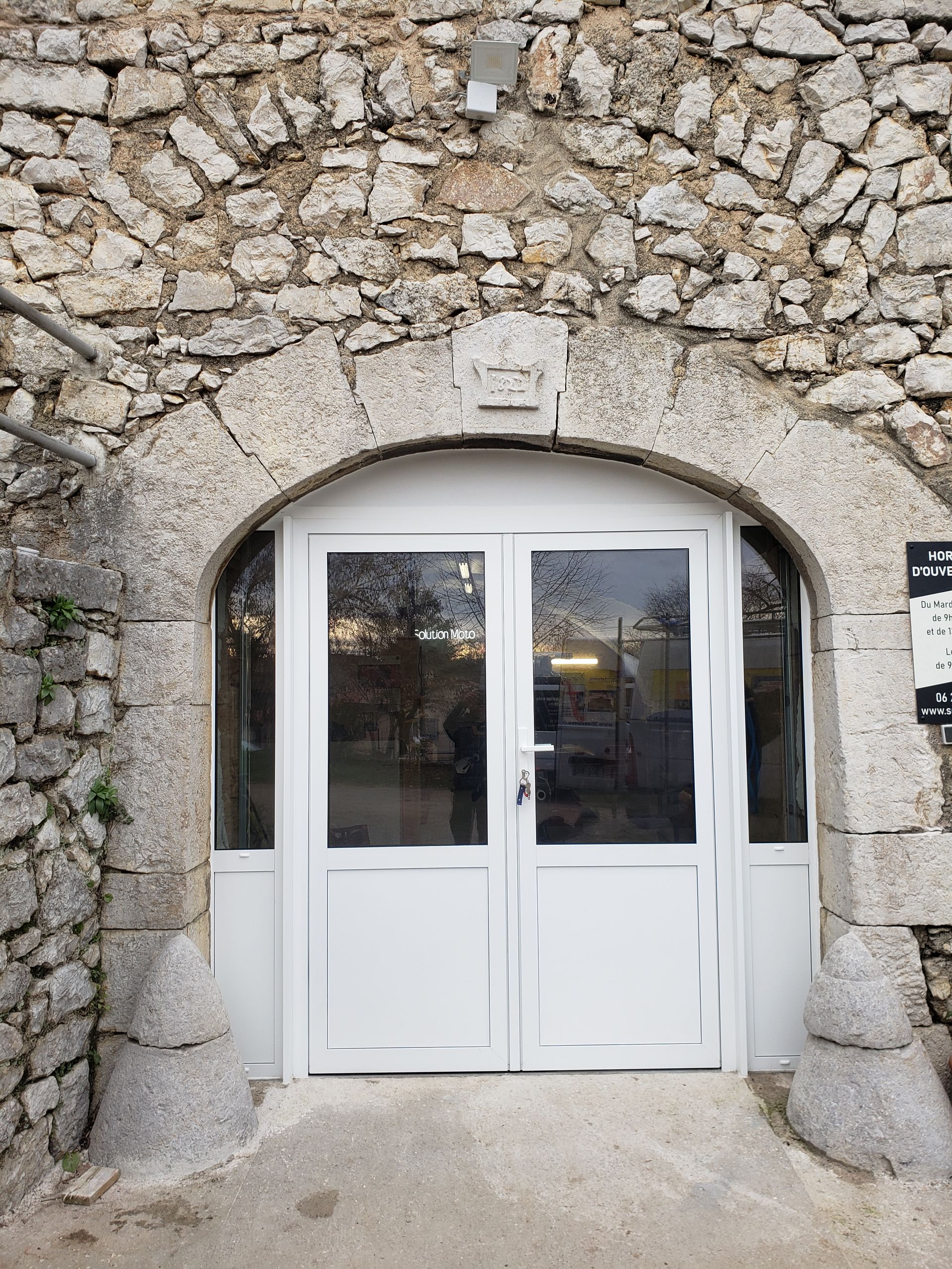 Porte d'entrée blanche dans arche de maison en pierre