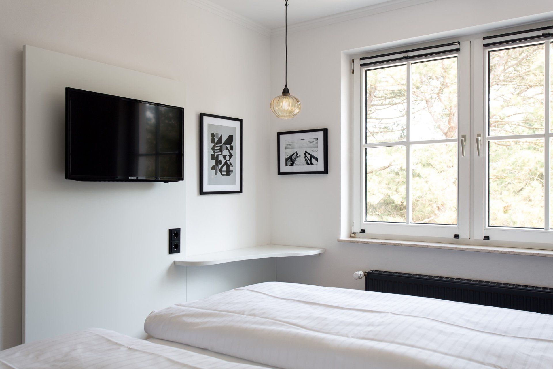 Ein Schlafzimmer mit zwei Betten, einem Fernseher und einem Fenster.