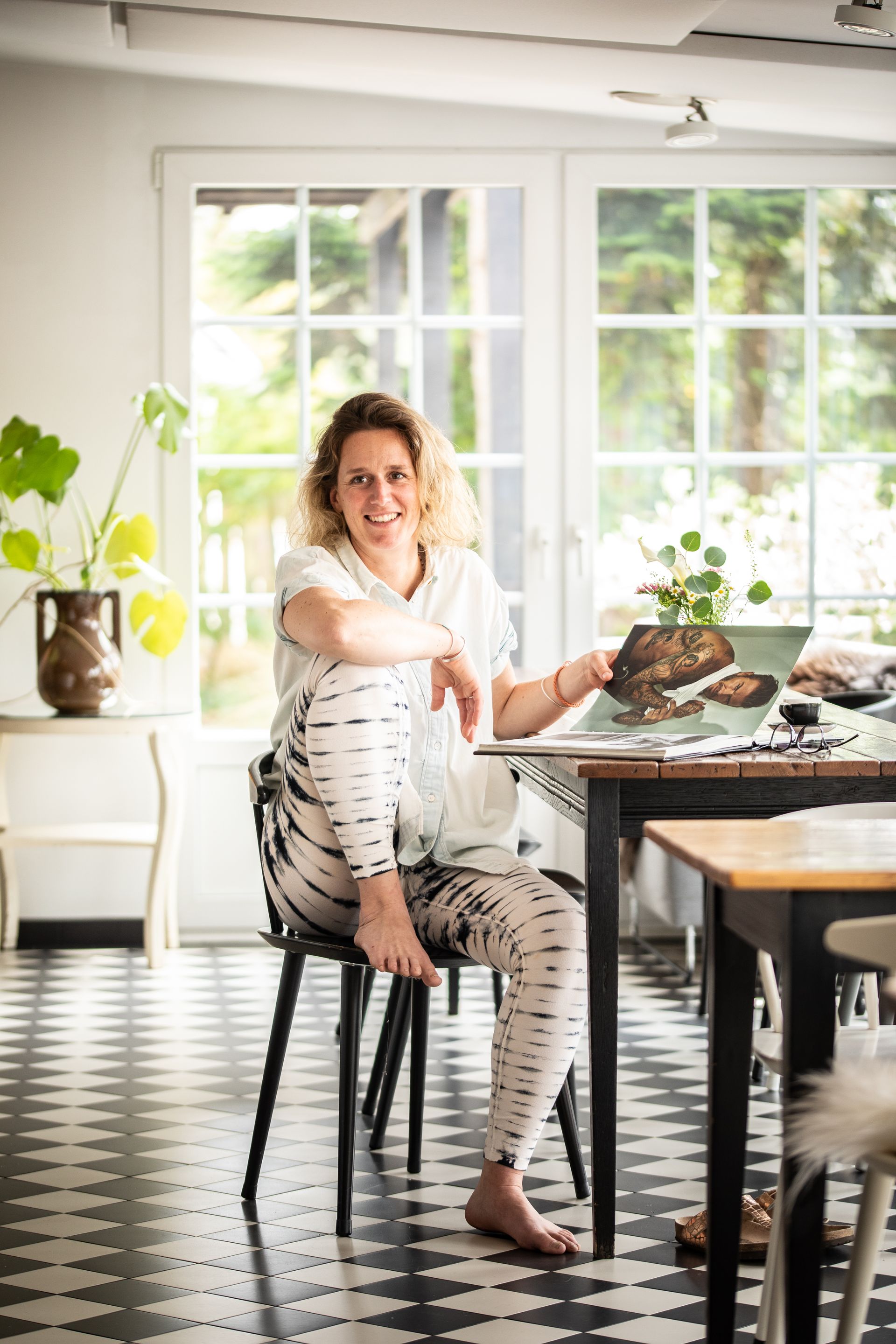 Eine Frau sitzt auf einem Hocker vor einem Tisch.