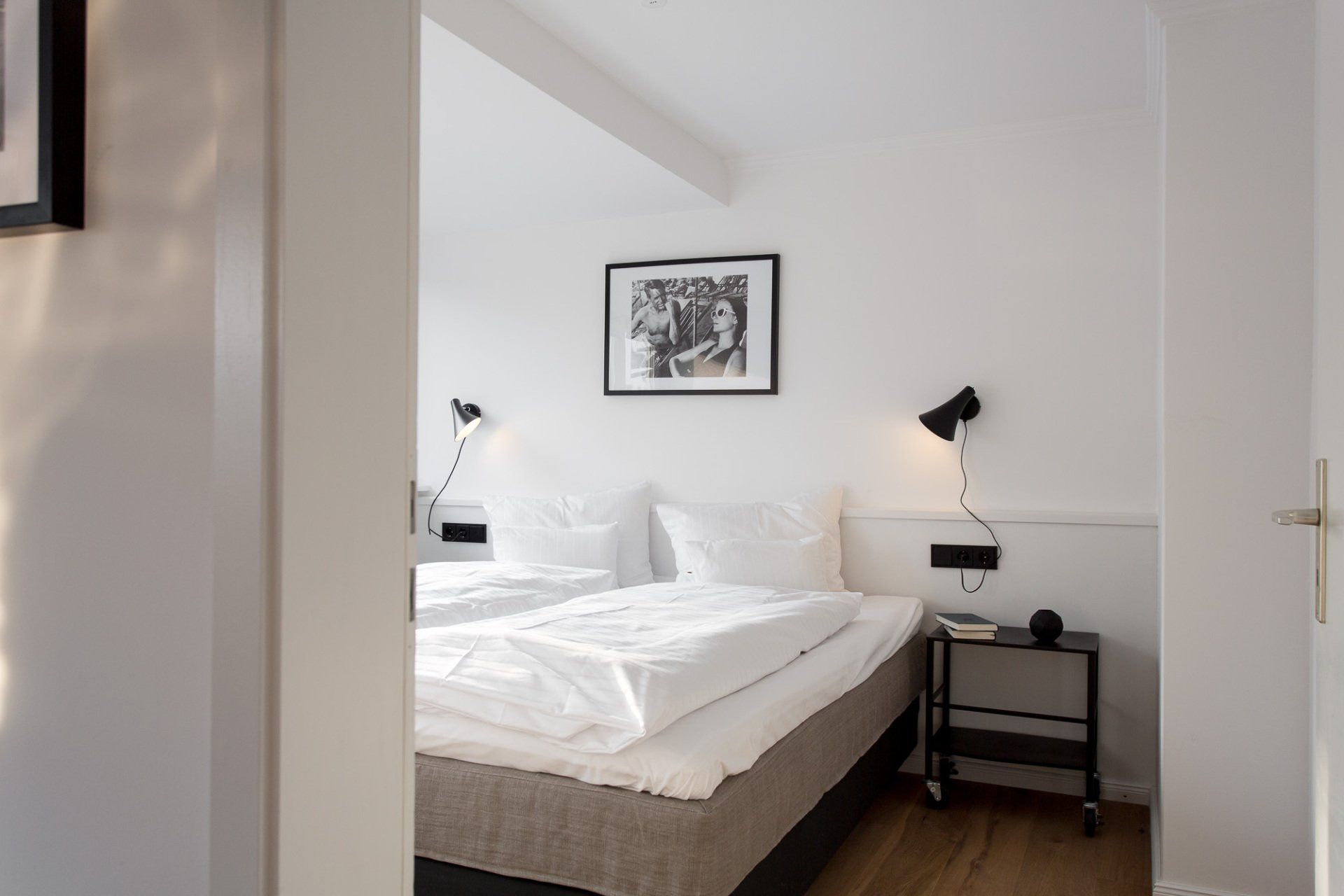 Ein Schlafzimmer mit Bett, Nachttisch, Lampe und Bild an der Wand.