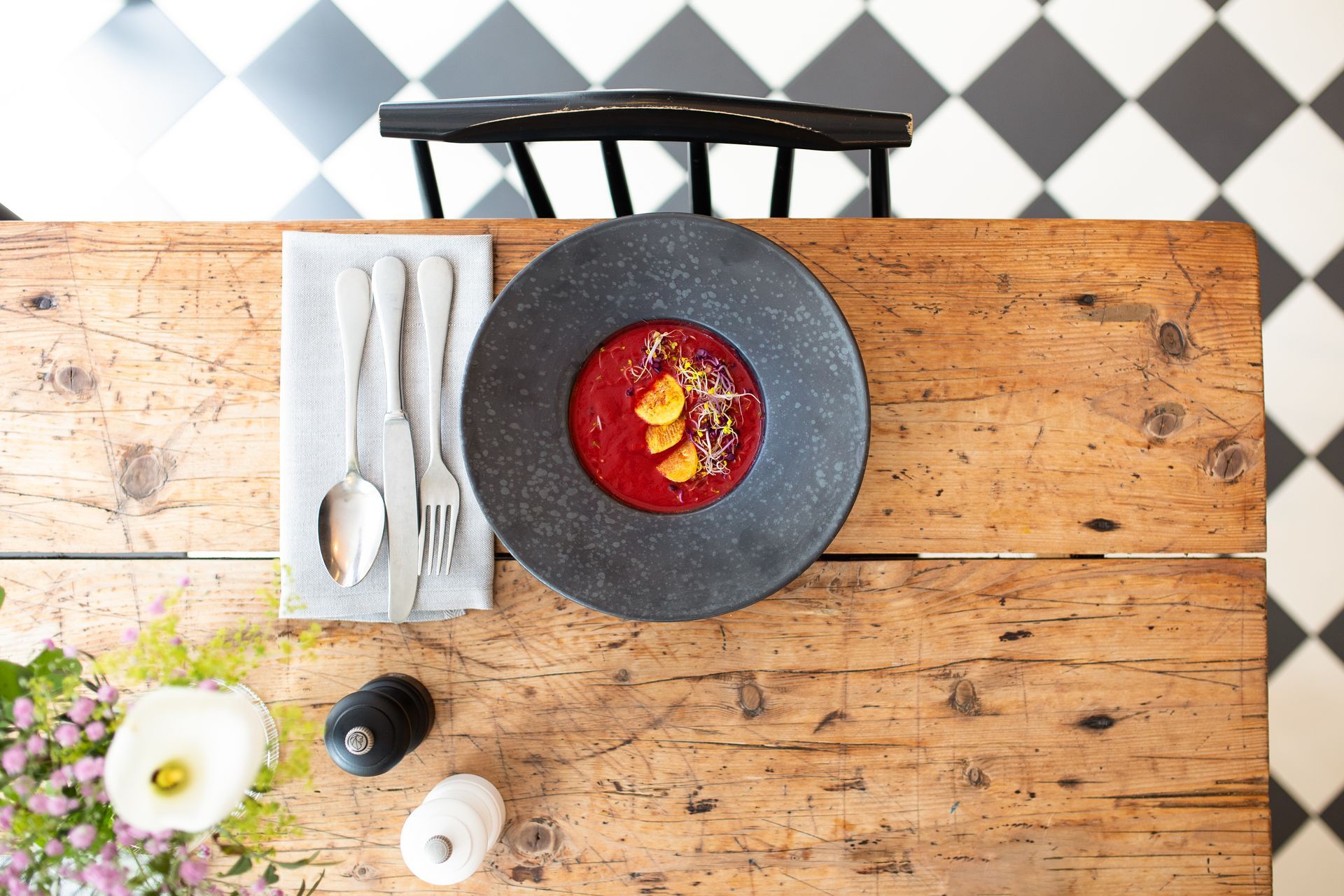 Ein Holztisch mit einer Schüssel Suppe und Besteck darauf.
