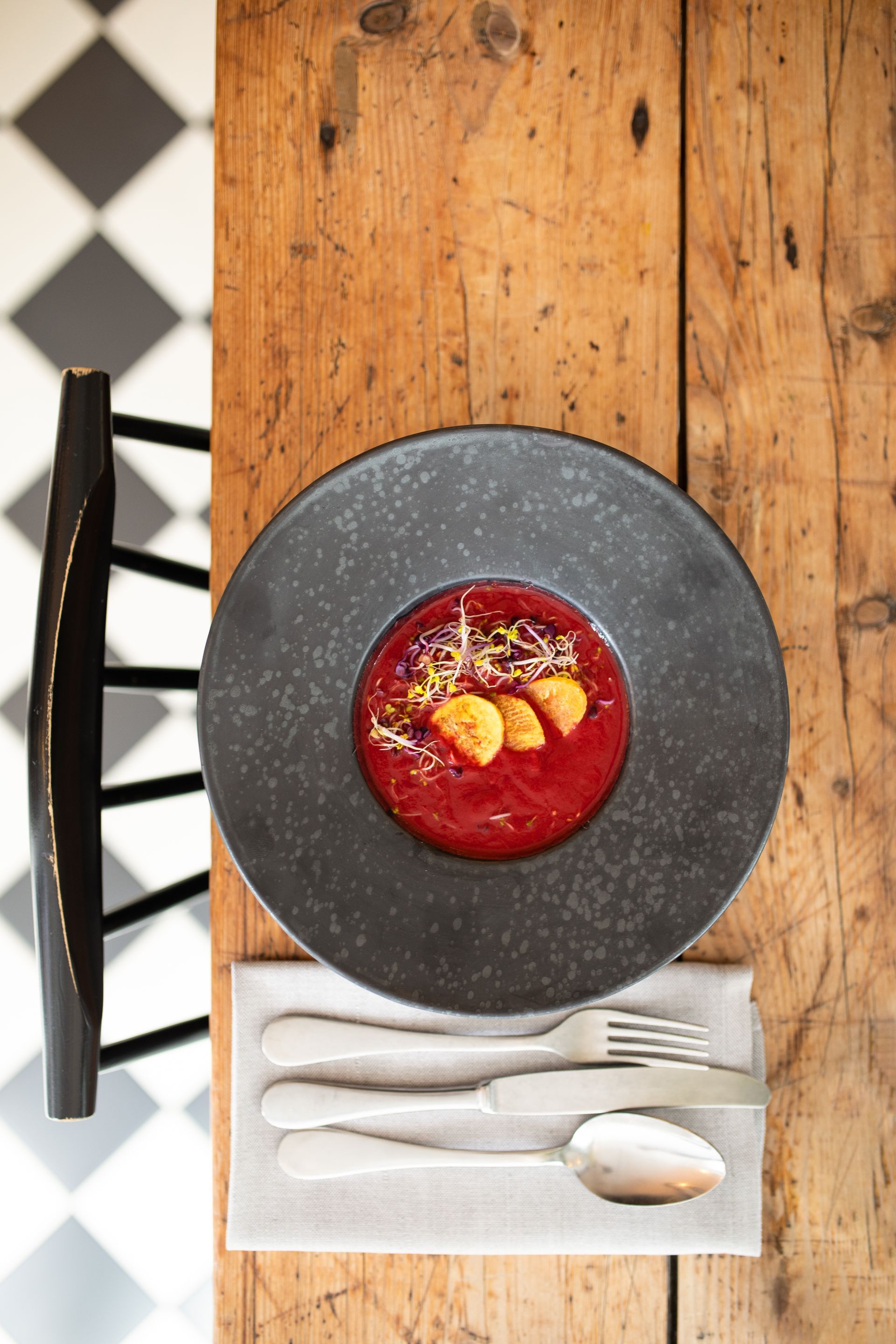 Auf einem Holztisch steht eine Schüssel Suppe mit Besteck.