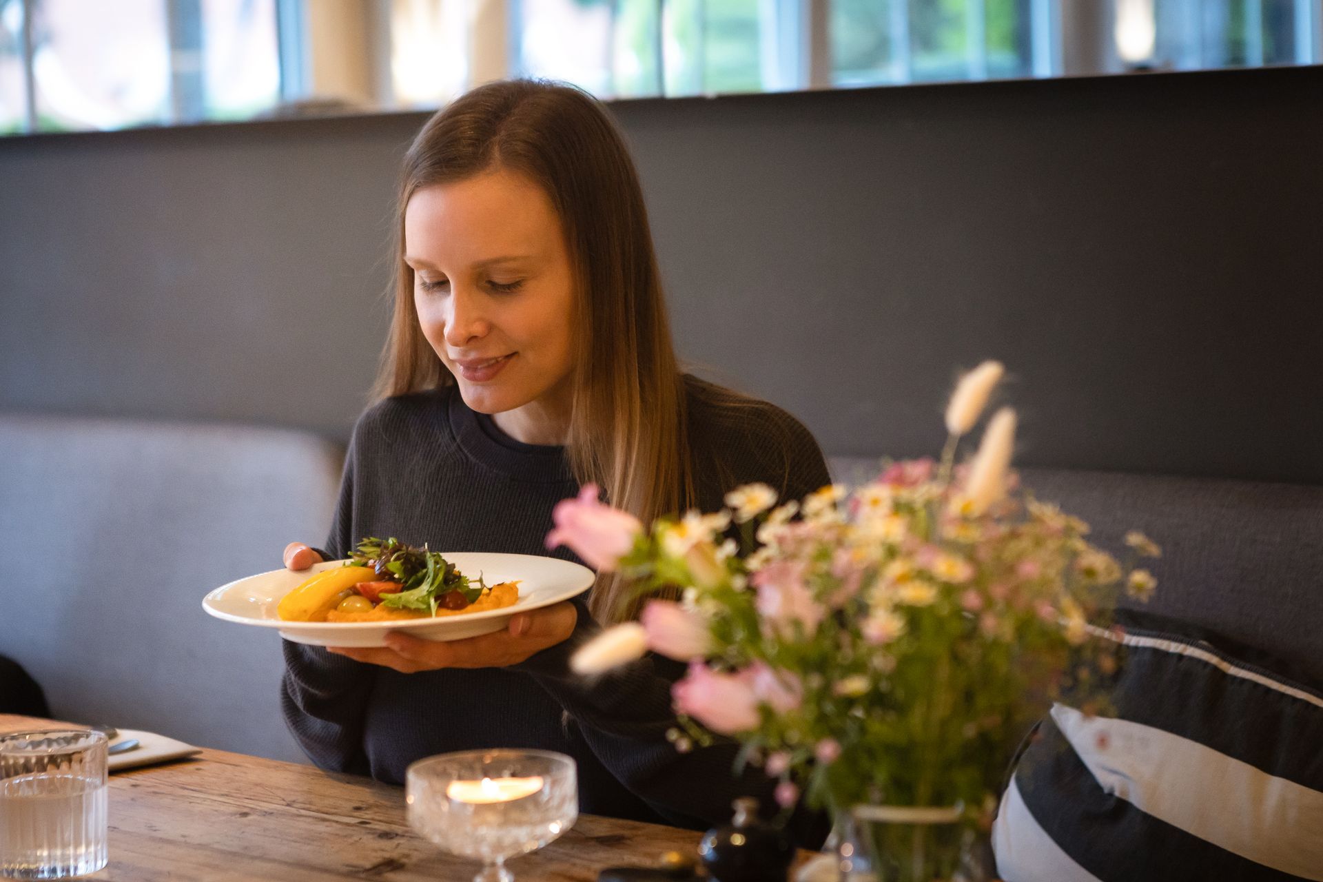 Eine Frau sitzt an einem Tisch und hält einen Teller mit Essen.