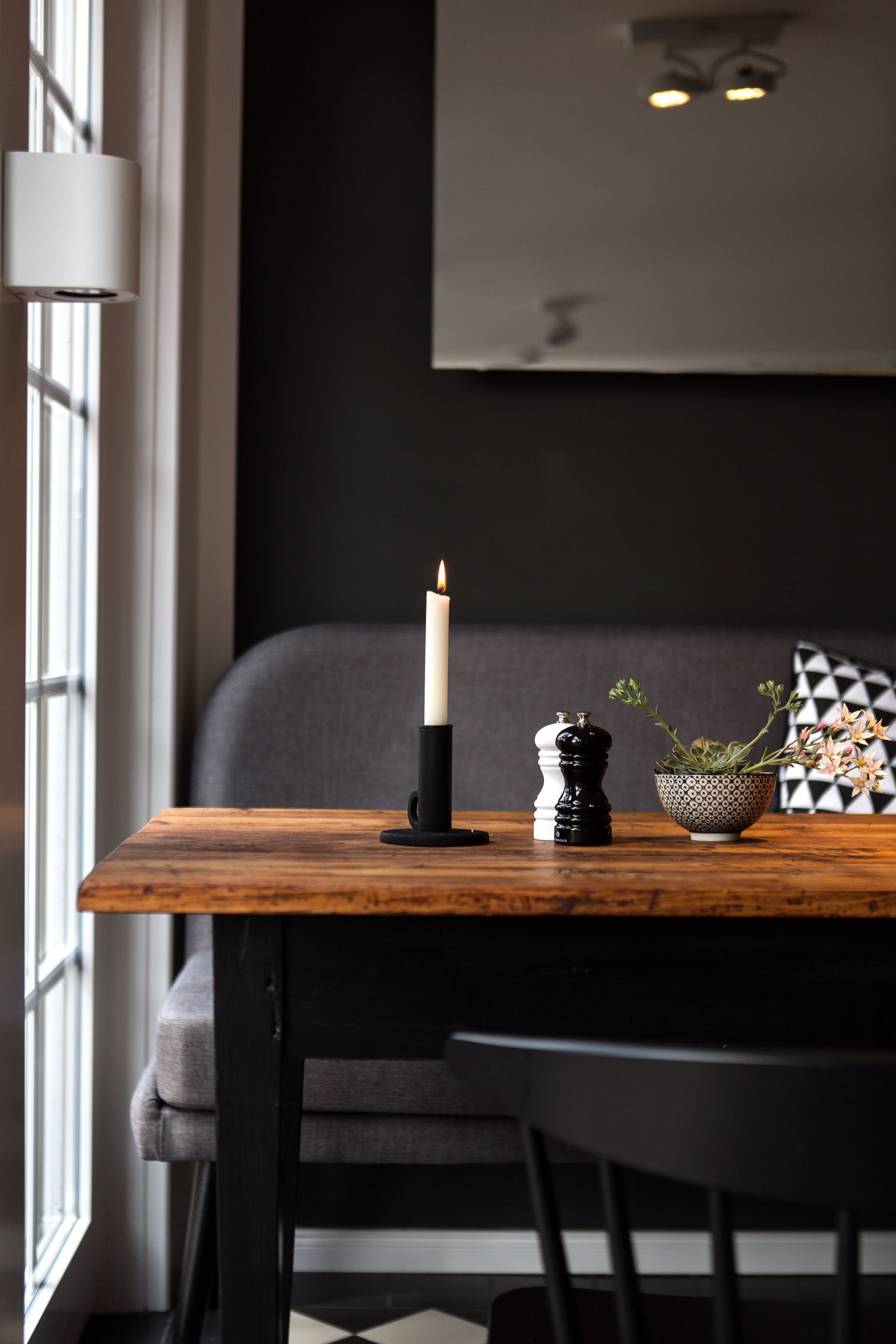 Ein Holztisch mit einer Kerze und einem Salz- und Pfefferstreuer darauf.