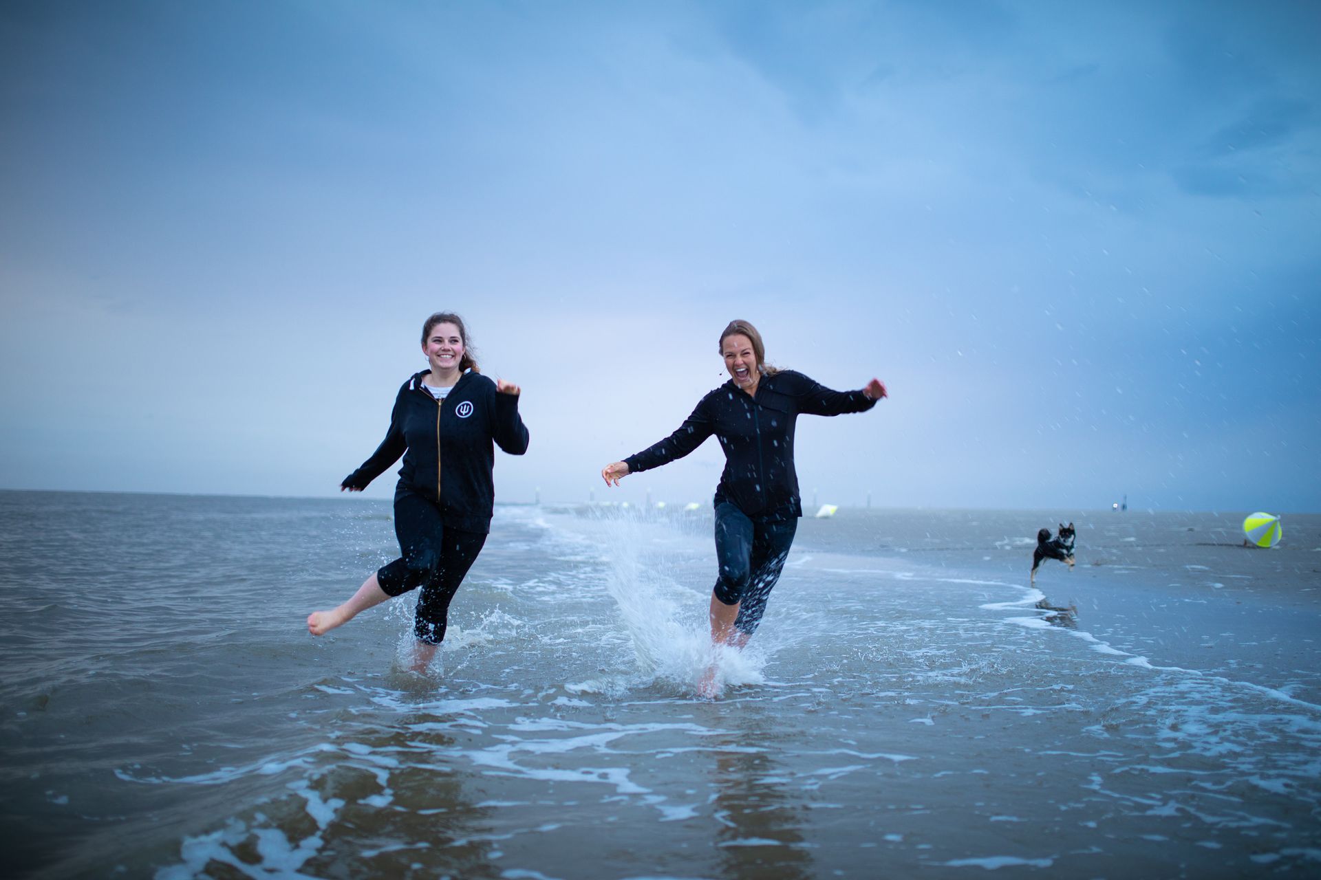 Zwei Frauen laufen an einem Strand im Wasser.