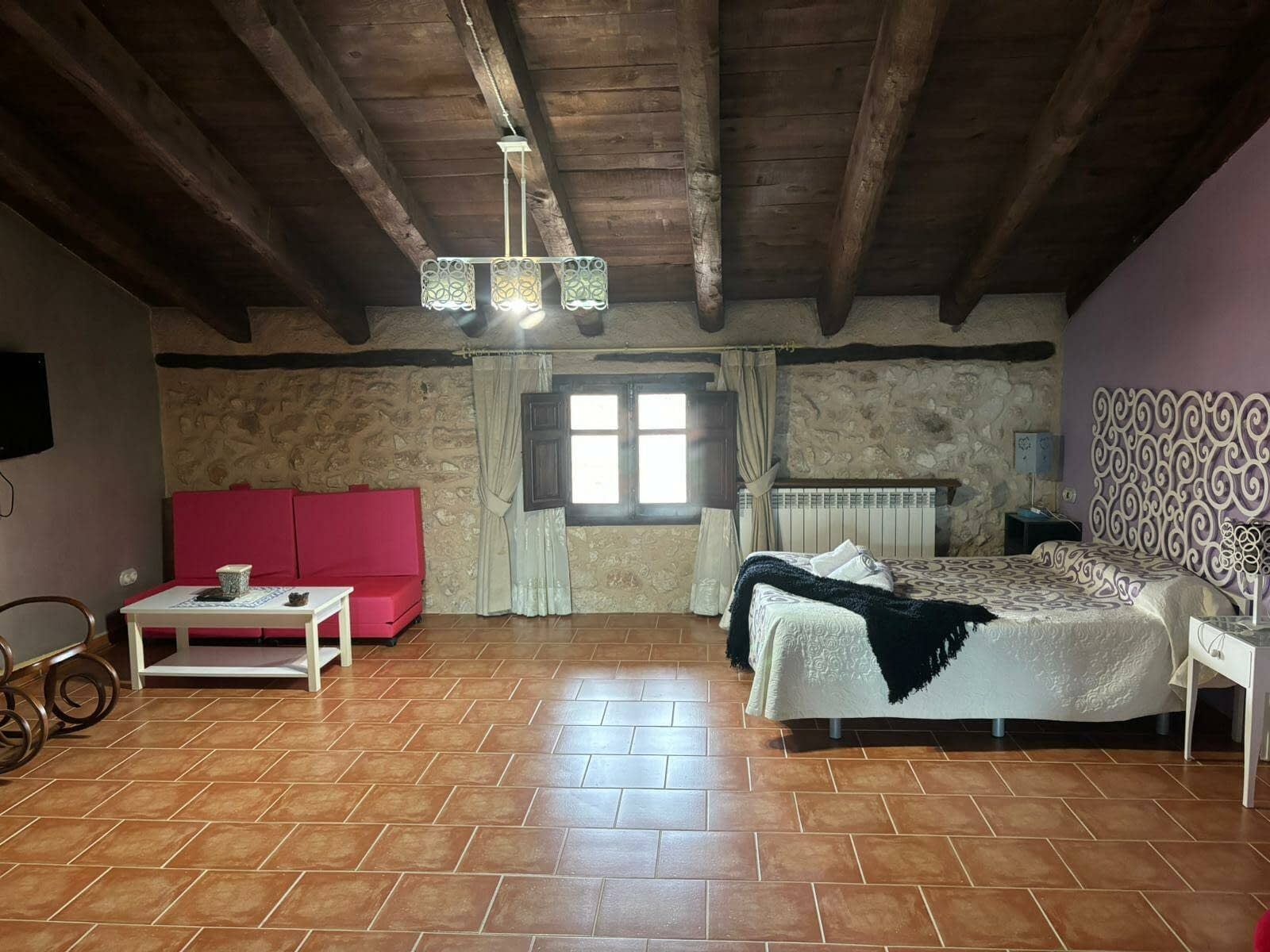 Una sala de estar con una cama, un sofá, una mesa de café y una televisión.