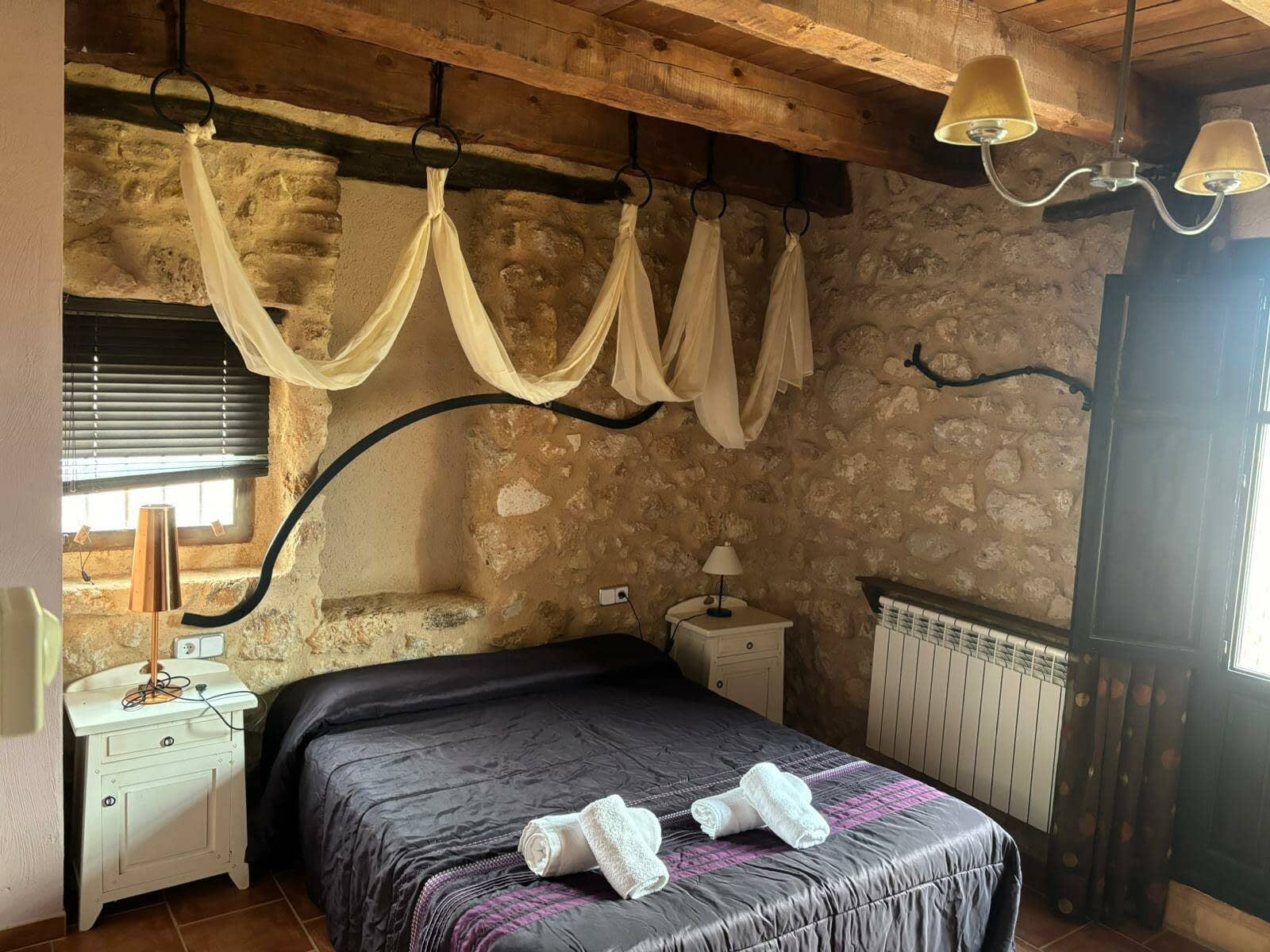 Un dormitorio con una cama, mesita de noche y una ventana.