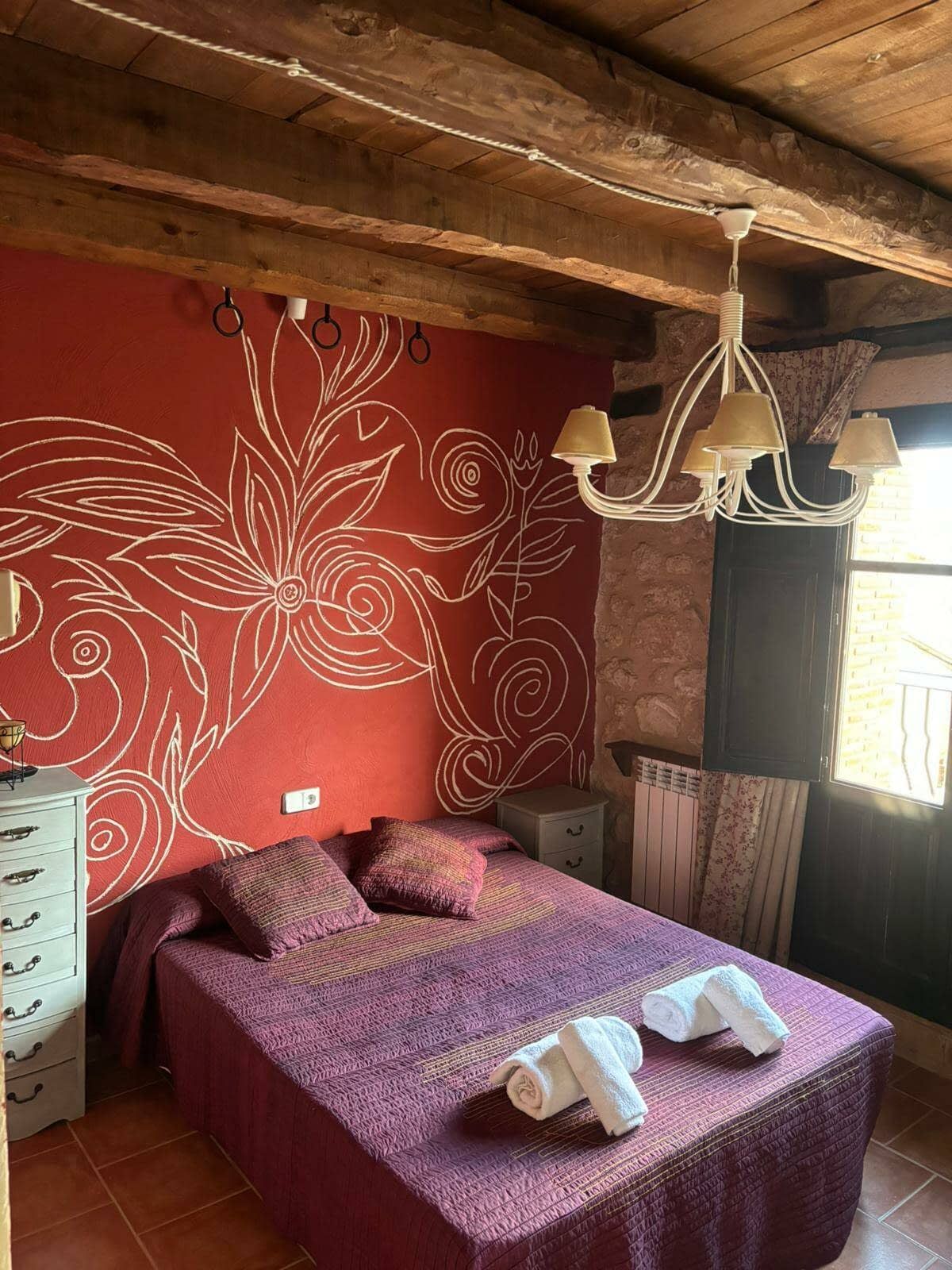 Un dormitorio con una cama, una cómoda y una lámpara de araña.