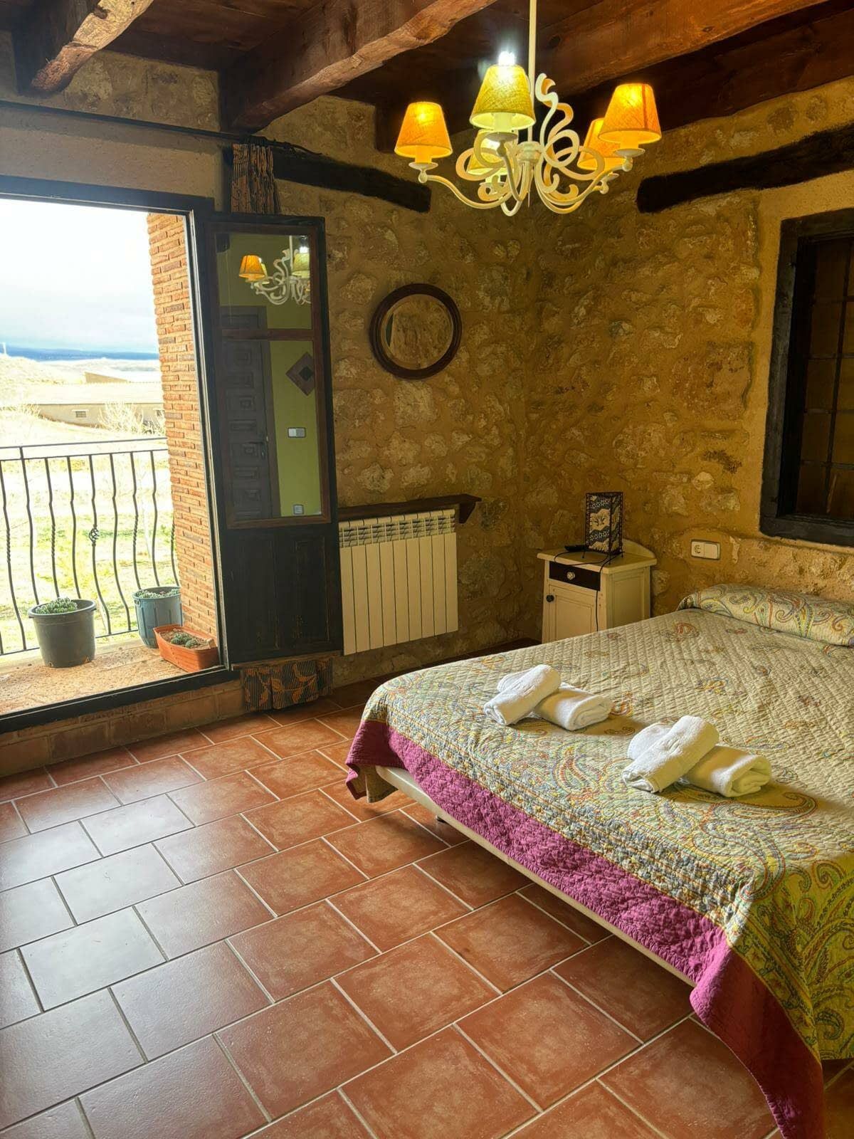 Un dormitorio con una cama y un balcón con una lámpara de araña colgando del techo.