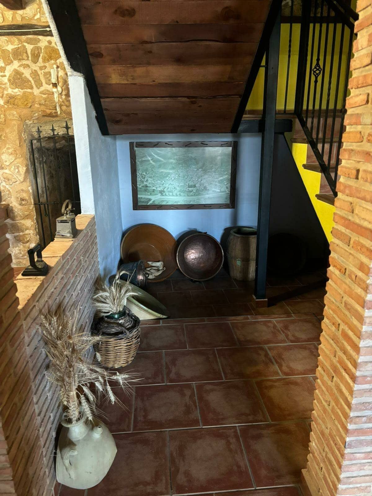 Un pasillo con una escalera de madera y una pared de ladrillo.