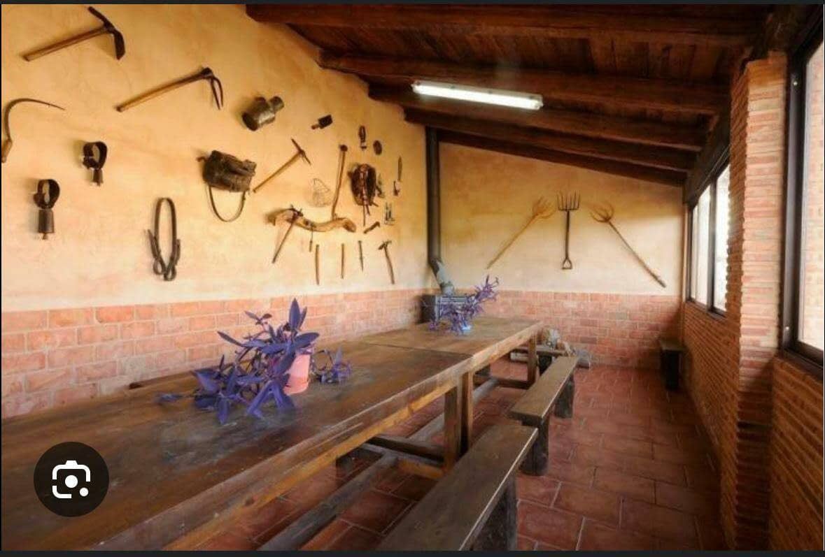 Una habitación con una larga mesa de madera y bancos y herramientas en la pared.