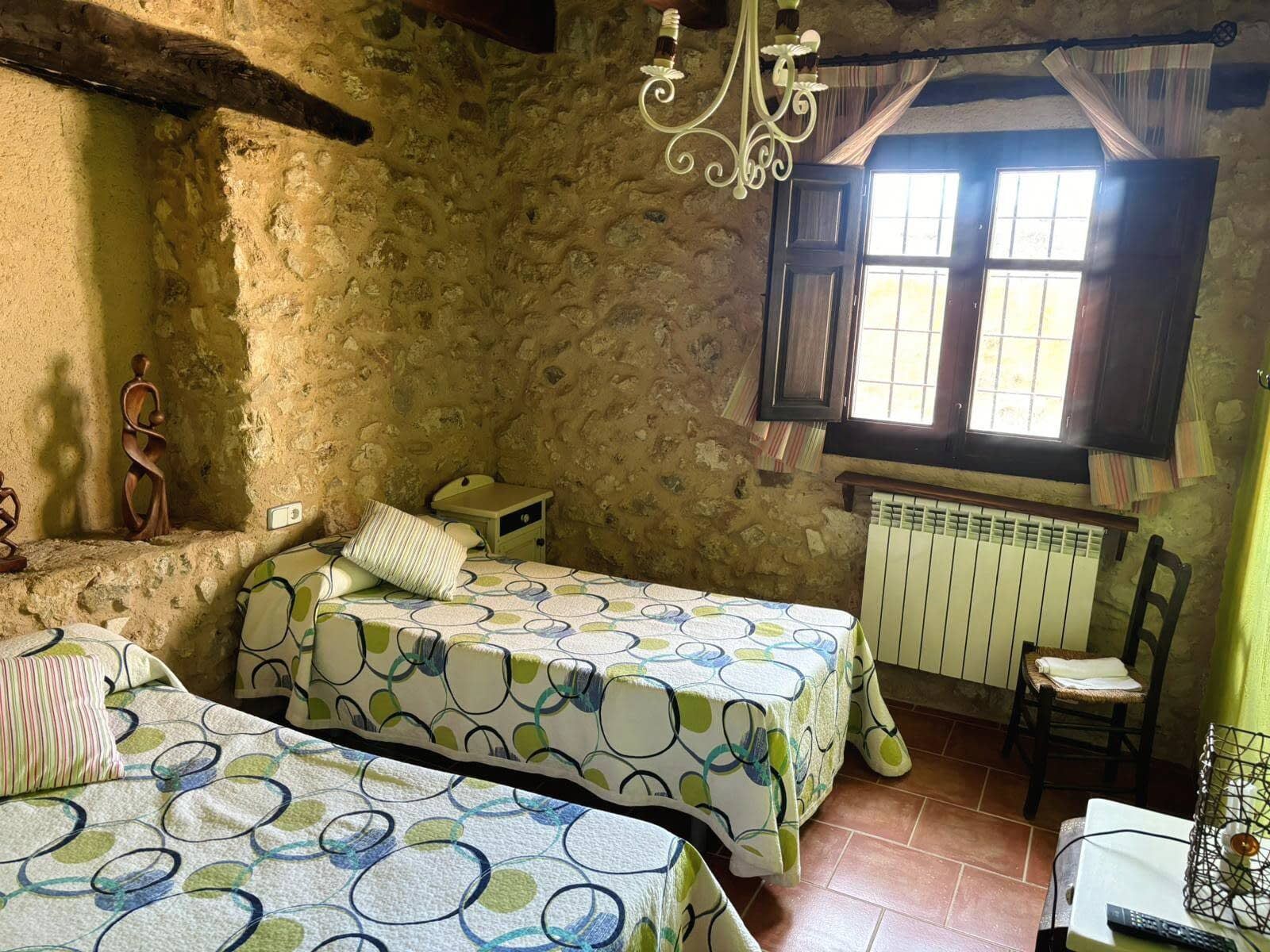 Un dormitorio con dos camas, una silla y una ventana.