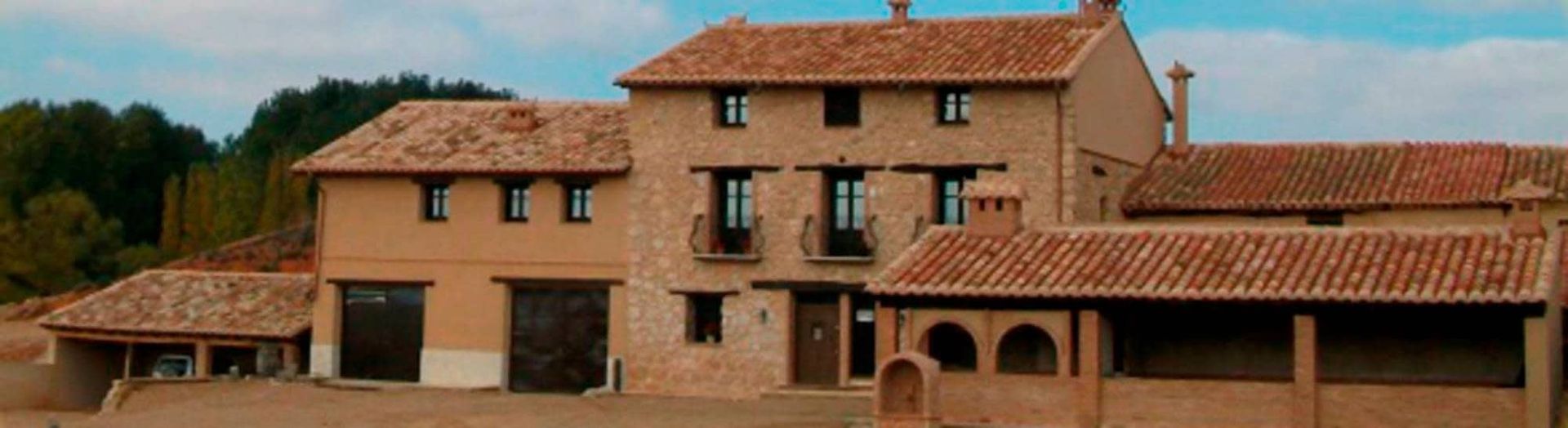 Una casa grande con techo de tejas rojas está rodeada de árboles.