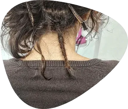Vista posterior de una persona con cabello oscuro peinado con pinzas. Dos mechones sueltos cuelgan.
