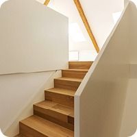 Holztreppe mit weissen Wänden und hellem Geländer in einem hellen Interieur