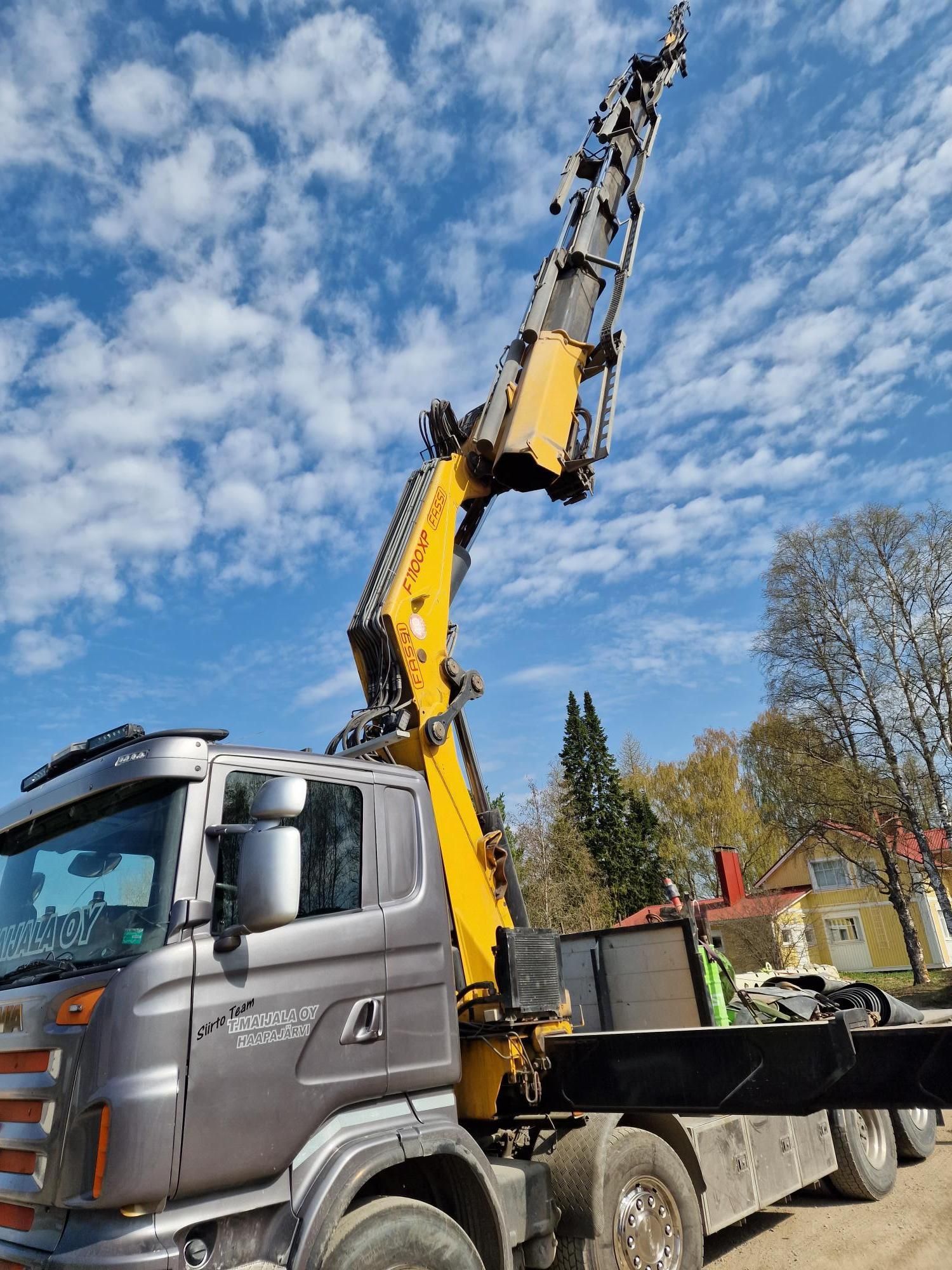Keltainen nosturiauto, jossa on pidennetty puominostolaite ulkona sinisen taivaan alla