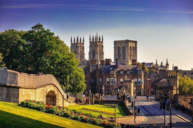 York Minster dominates a sunny cityscape with lush green lawns and blue sky.