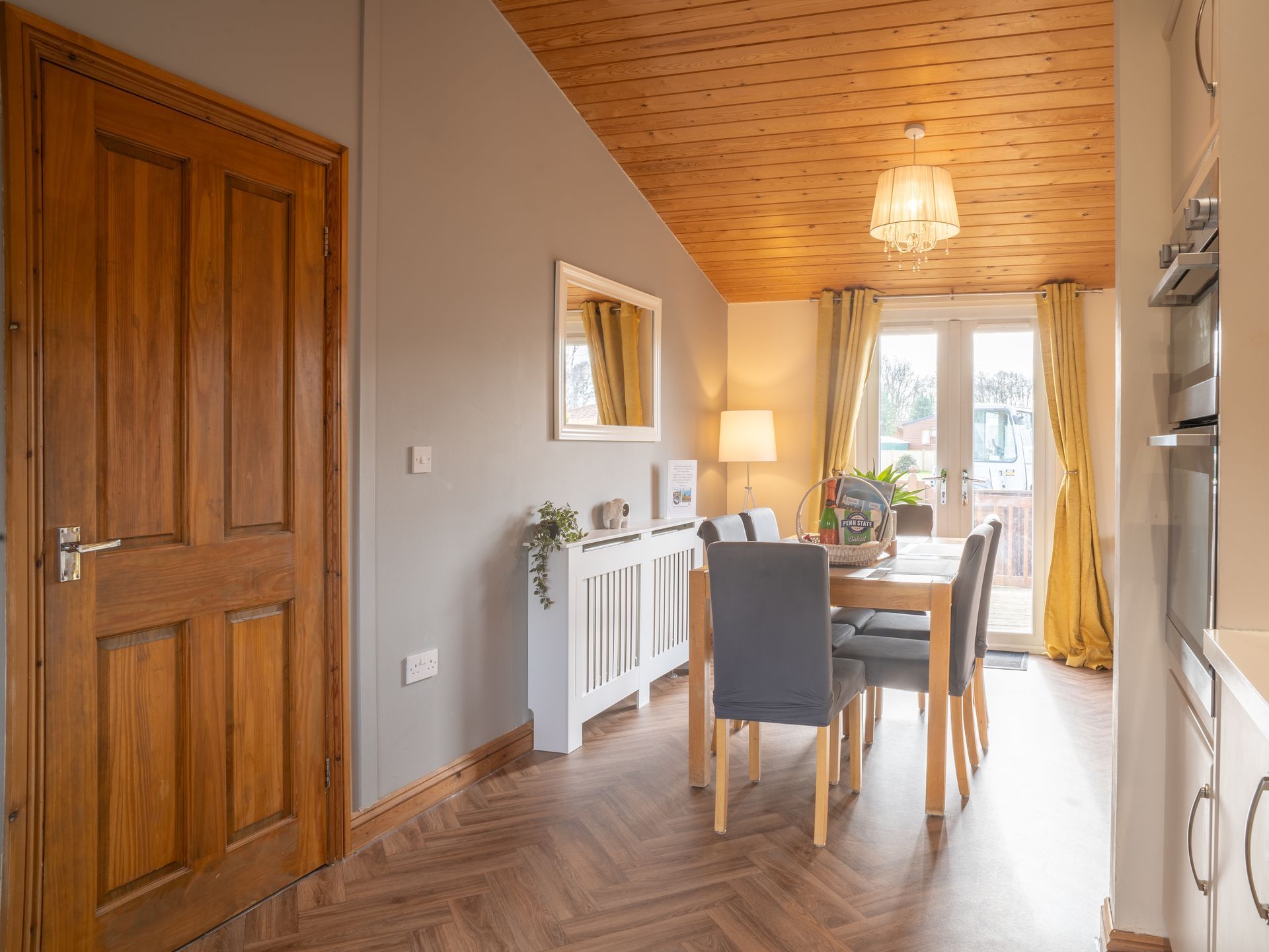 Dining area with wooden door, gray walls, dining table, and french doors.
